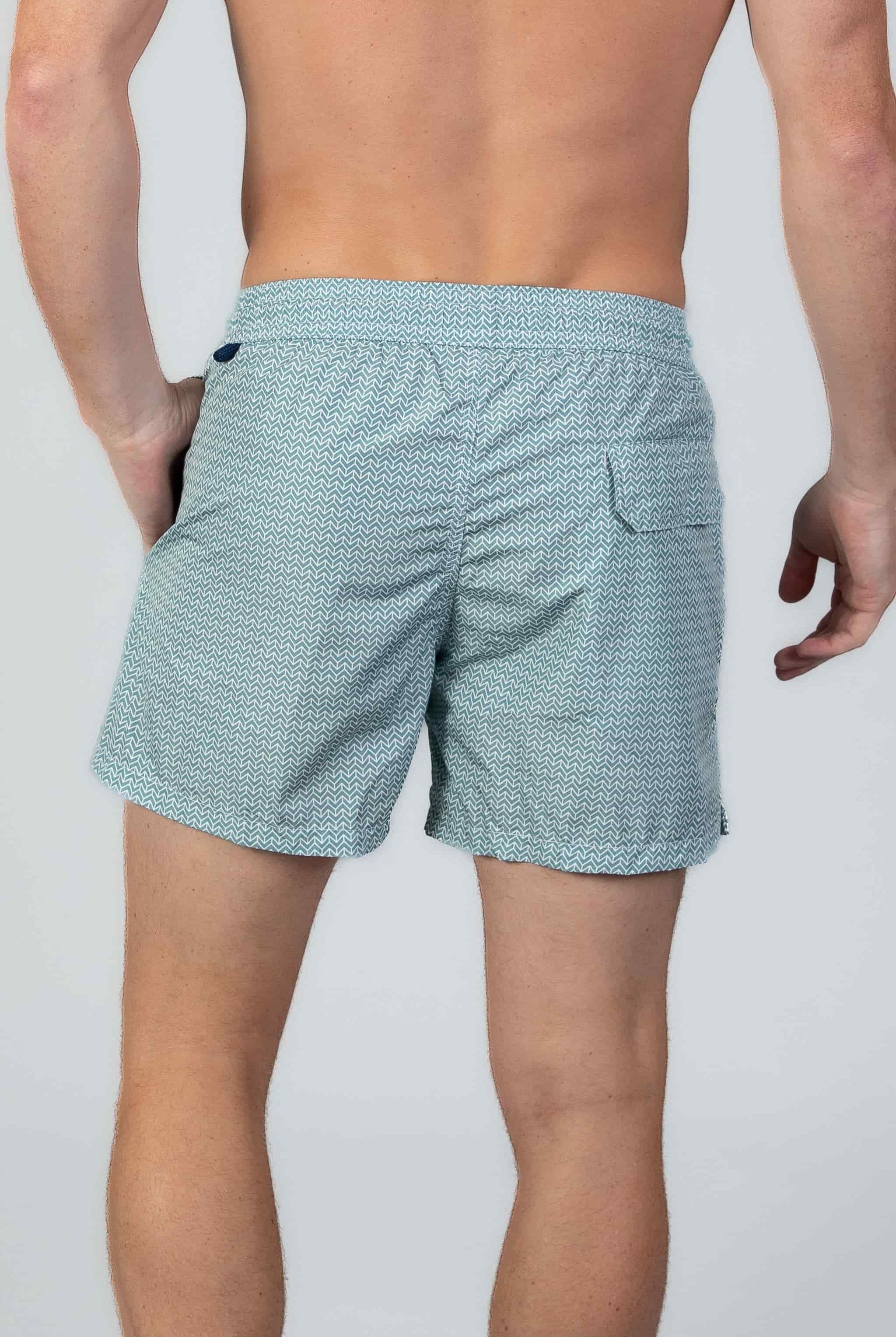 Arrow patterned swim shorts in Aqua turquoise with a magnetic back pocket on light gray background