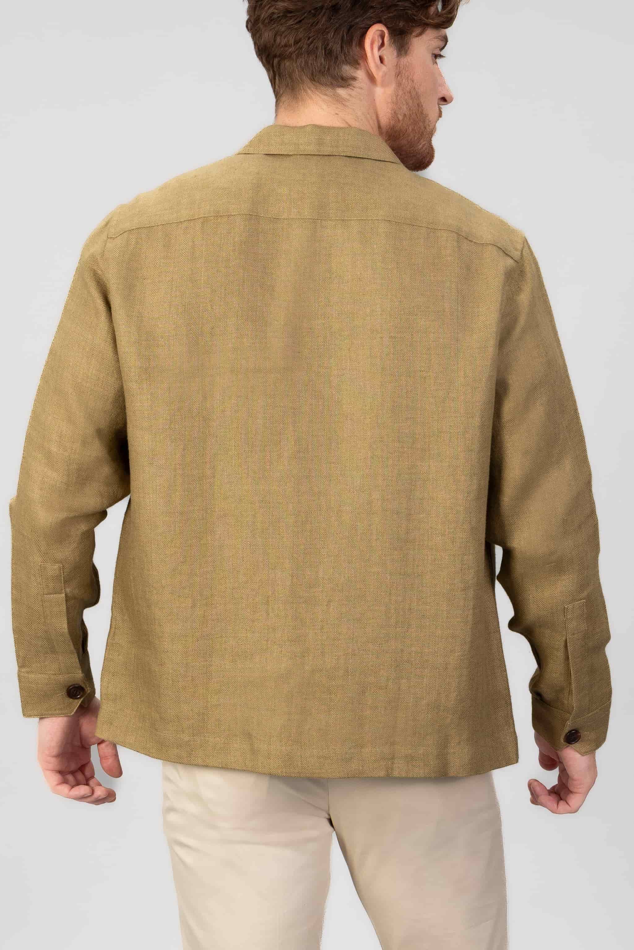 Man wearing a copper brown over-shirt, shown from the back with light gray background