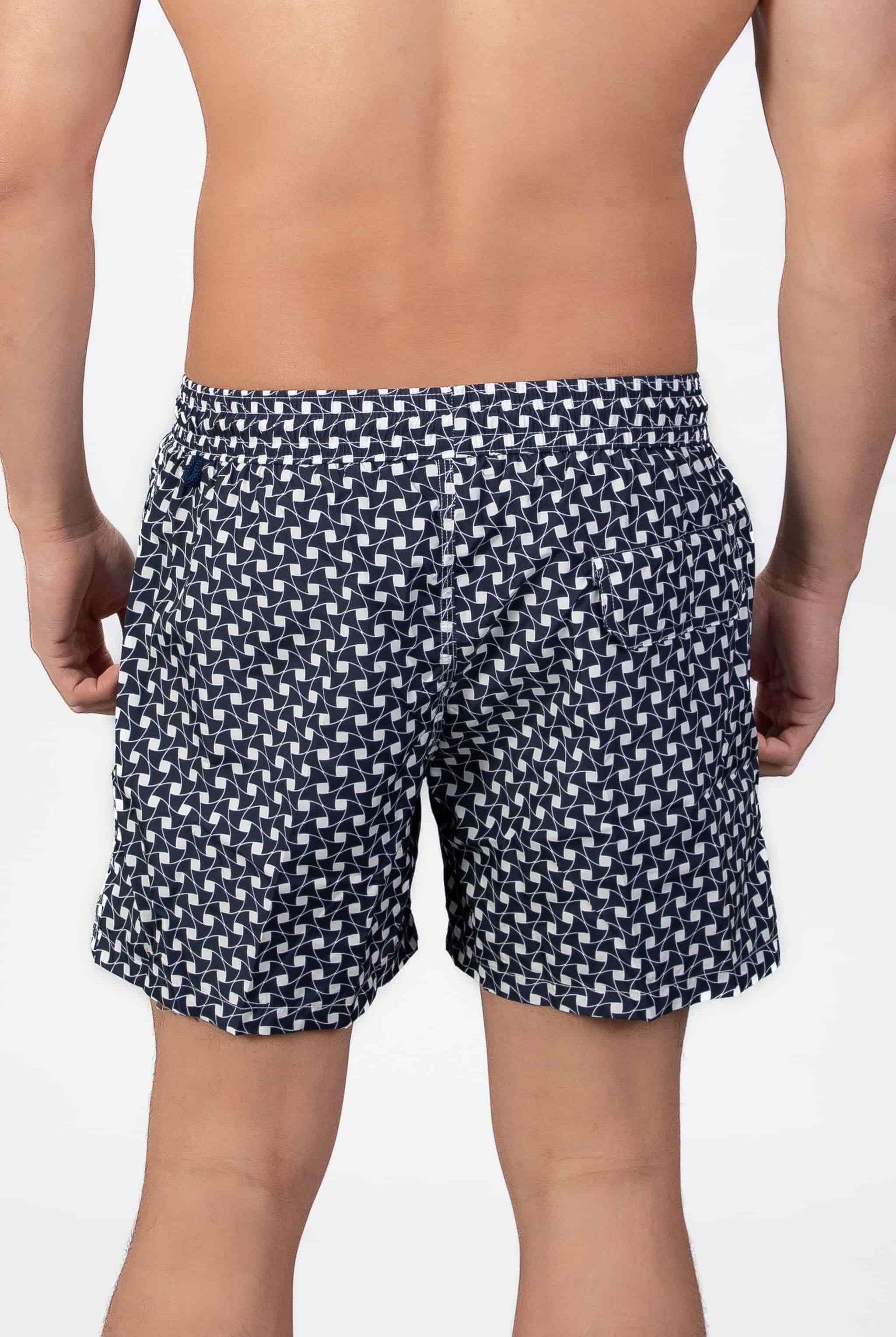 Back view of navy blue swim shorts with a subtle classic pattern and back pocket detail closing with a magnet.