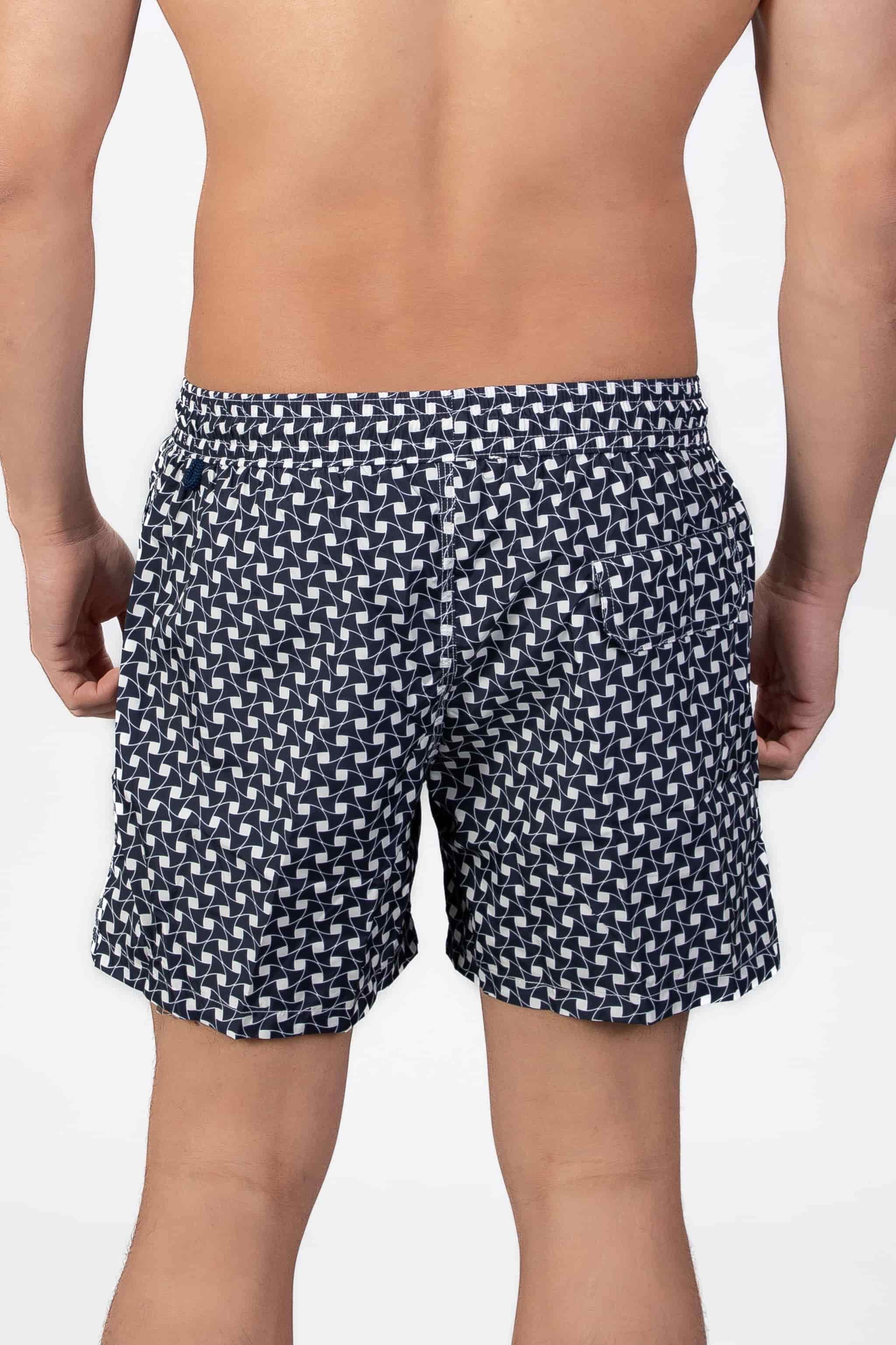 Back view of navy blue swim shorts with a subtle classic pattern and back pocket detail closing with a magnet.