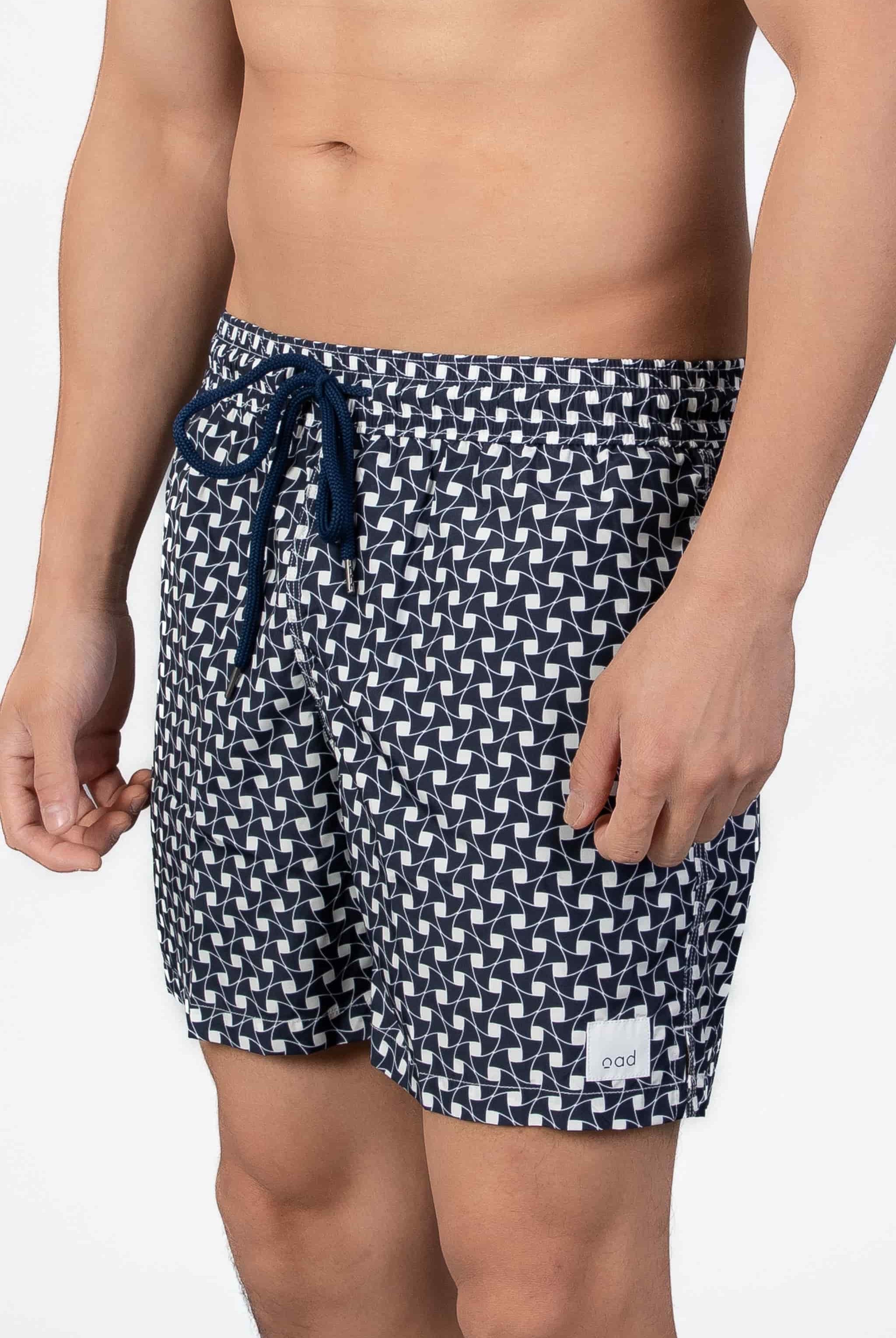 Aide view of navy blue swim shorts with a subtle classic pattern and navy string waist closure.