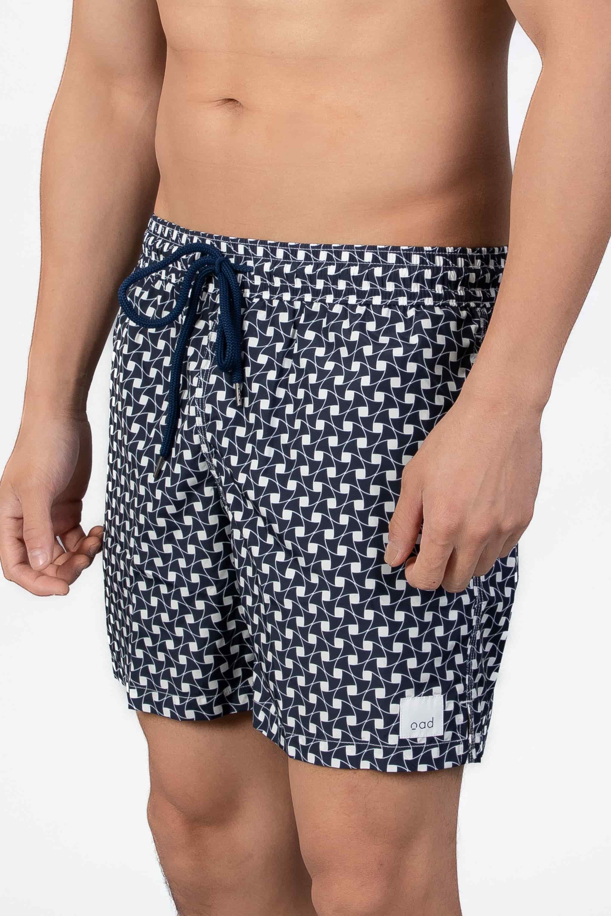 Aide view of navy blue swim shorts with a subtle classic pattern and navy string waist closure.