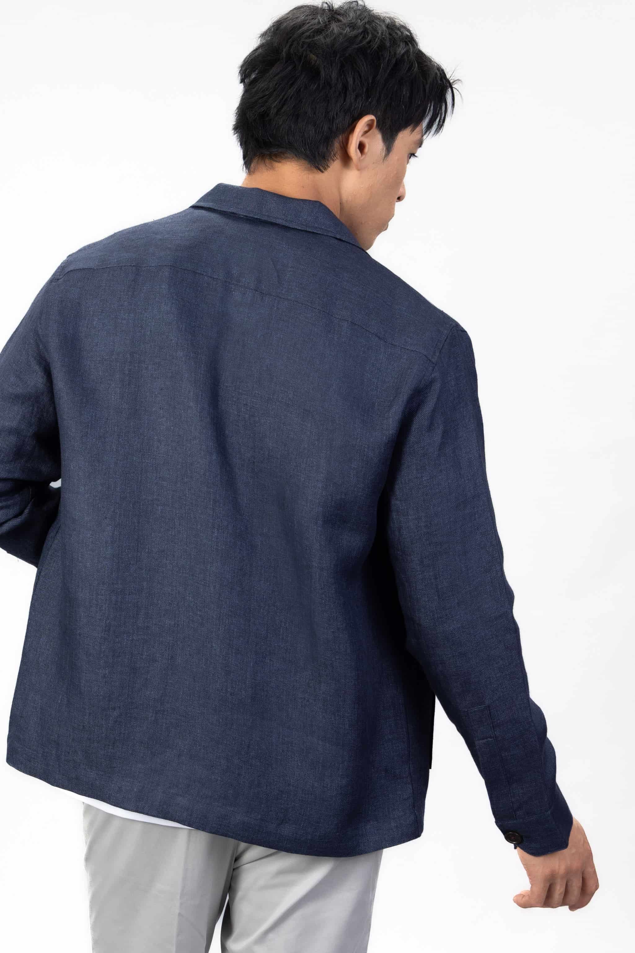 Person wearing a navy blue linen overshirt with gray chinos on a light gray background
