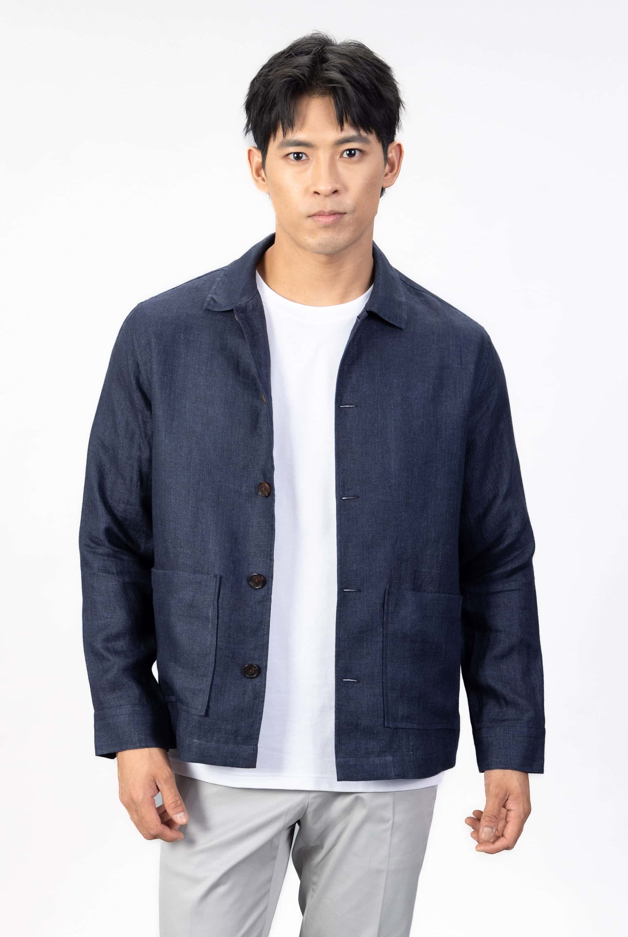 Person wearing a navy blue linen overshirt over a white T-shirt with gray chinos on a light gray background