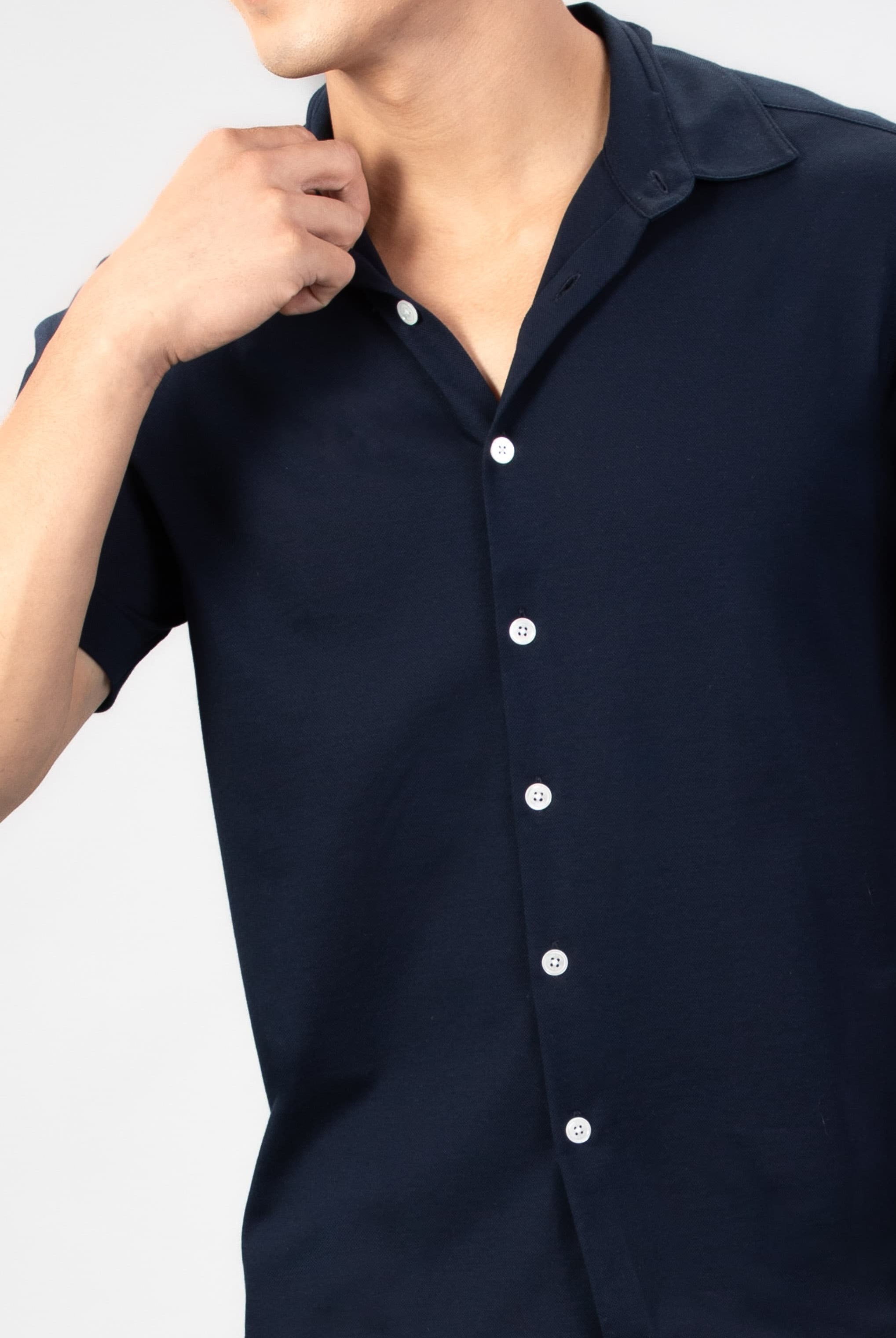 Navy blue piquet shirt worn by a person on a light gray background