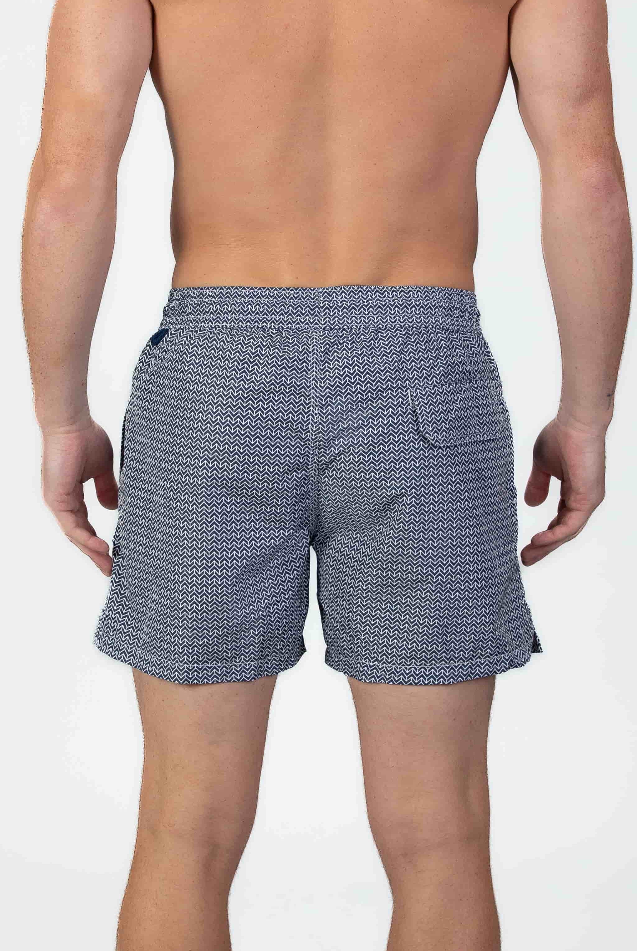 Back view of person wearing classic high end navy swim shorts with a white pattern and drawstring
