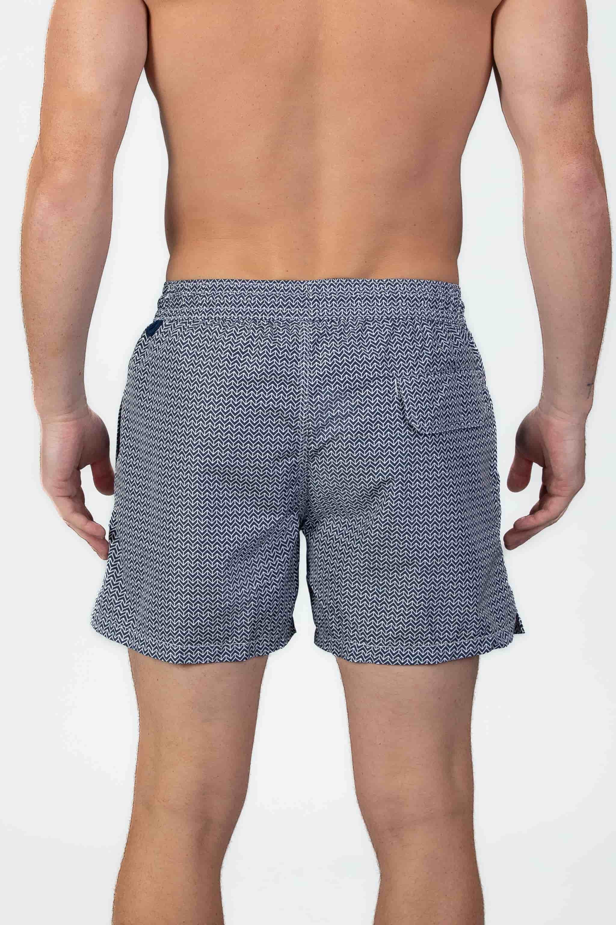 Back view of person wearing classic high end navy swim shorts with a white pattern and drawstring