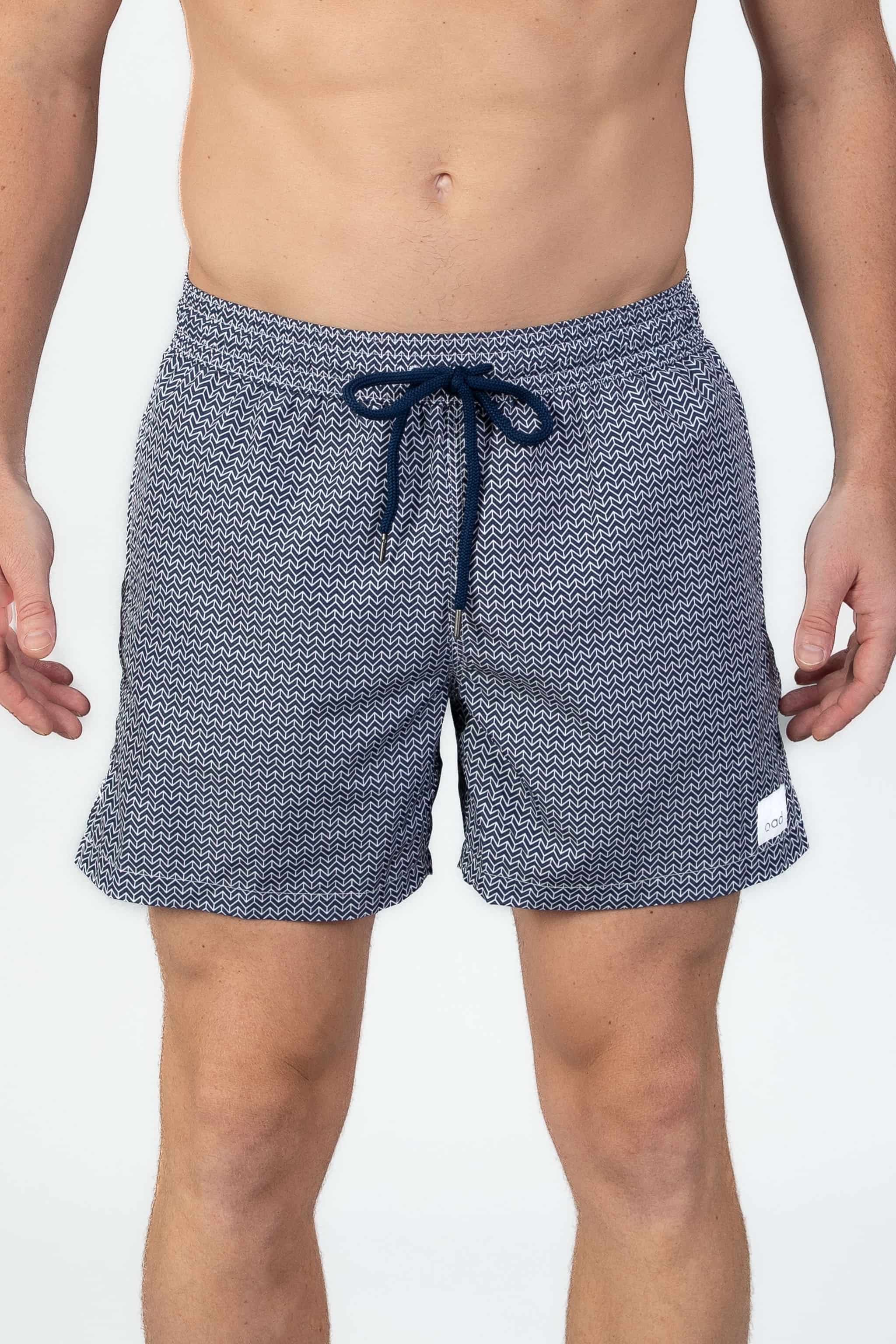 Front view of person wearing classic high end navy swim shorts with a white pattern and drawstring