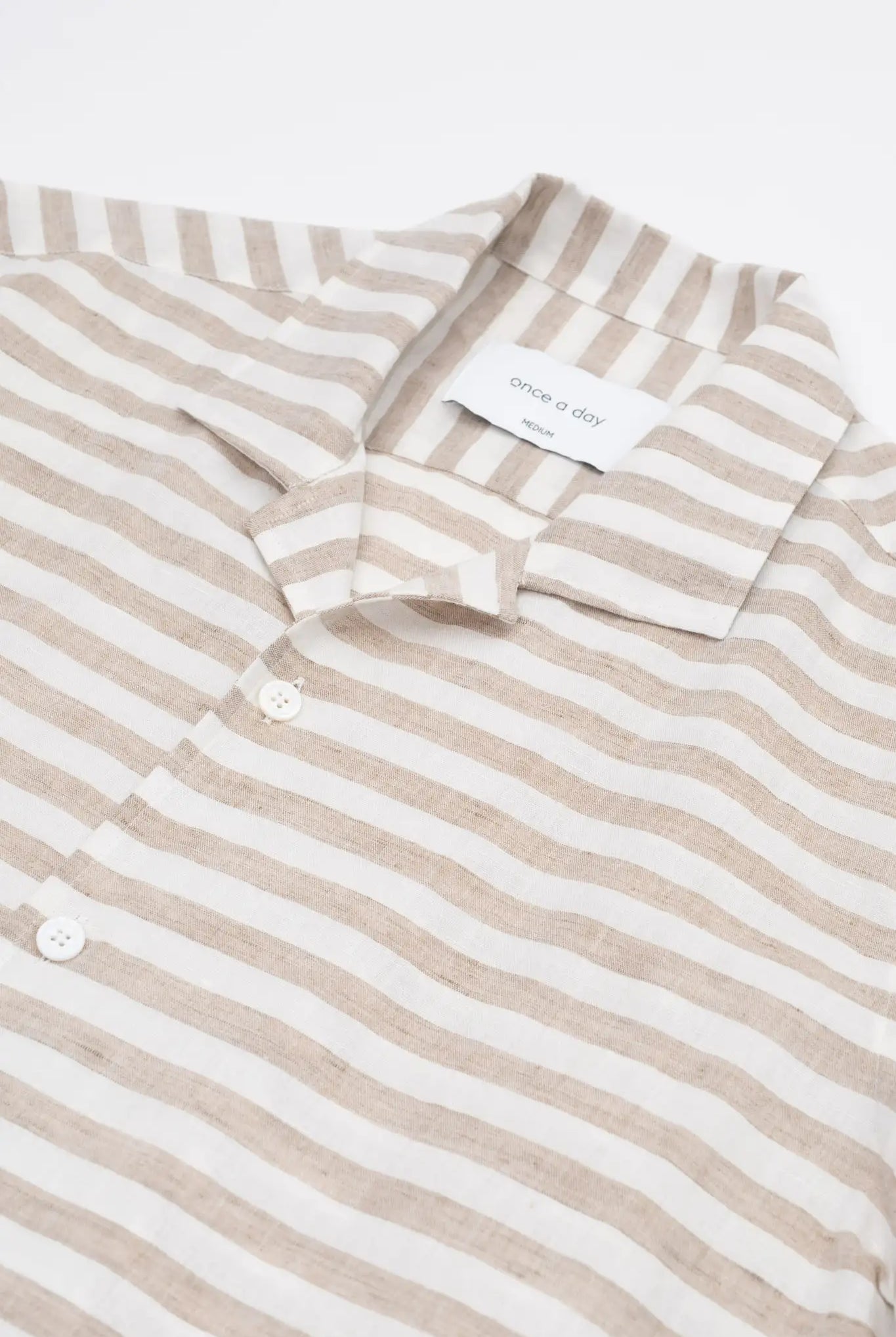 Beige and white striped linen shirt on a white background