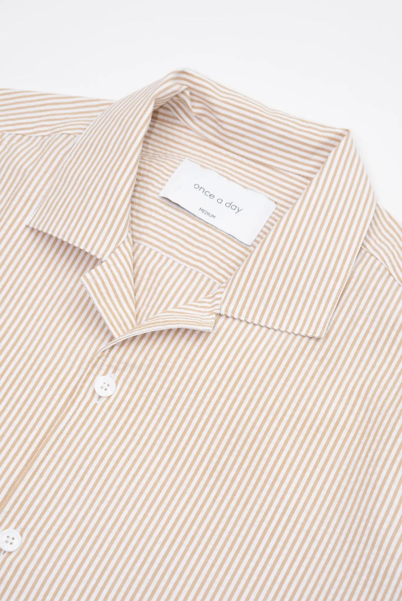 Beige striped camp collar shirt in seersucker fabric on a white background