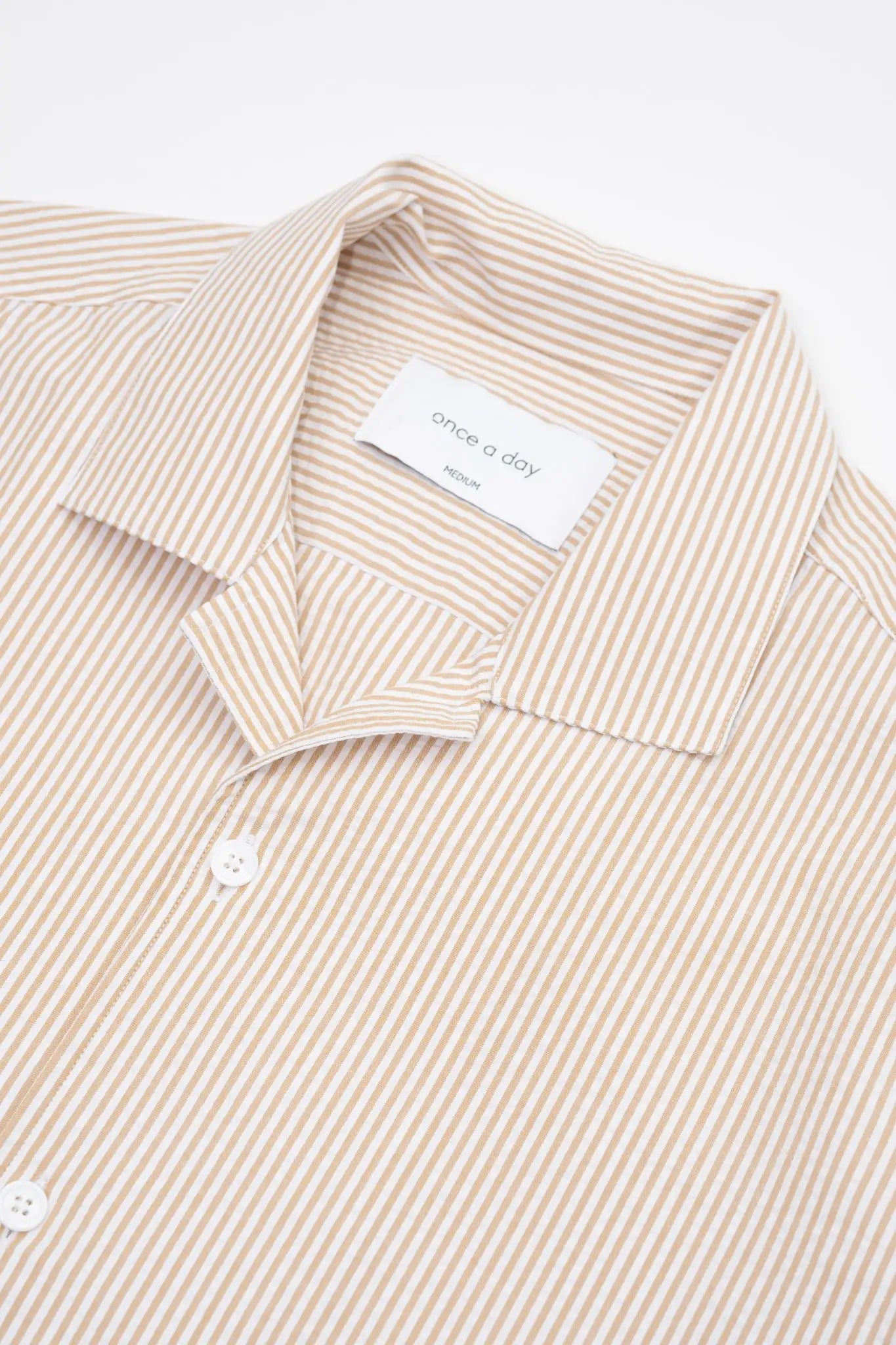 Beige striped camp collar shirt in seersucker fabric on a white background