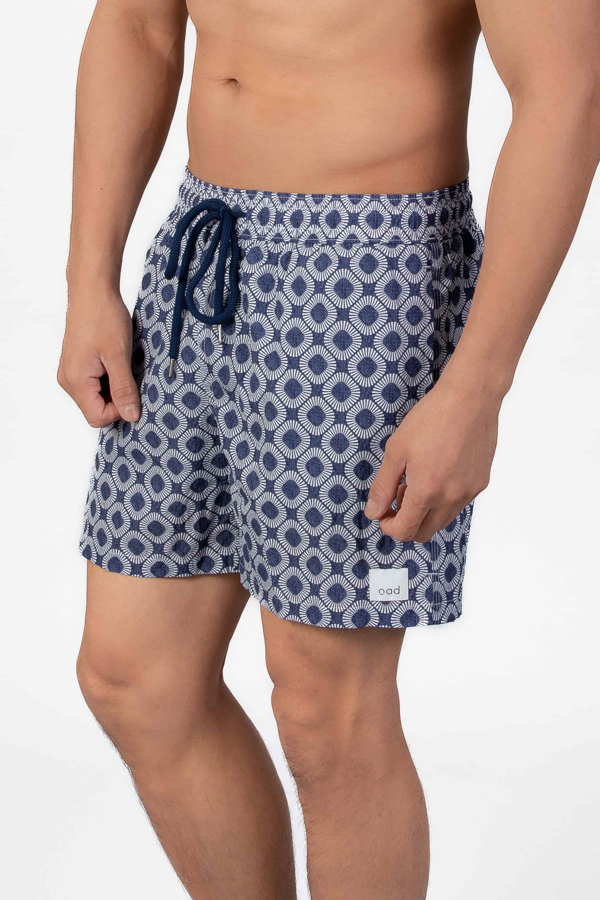 Man wearing blue patterned shorts in navy blue seersucker fabric and string closure on a plain background