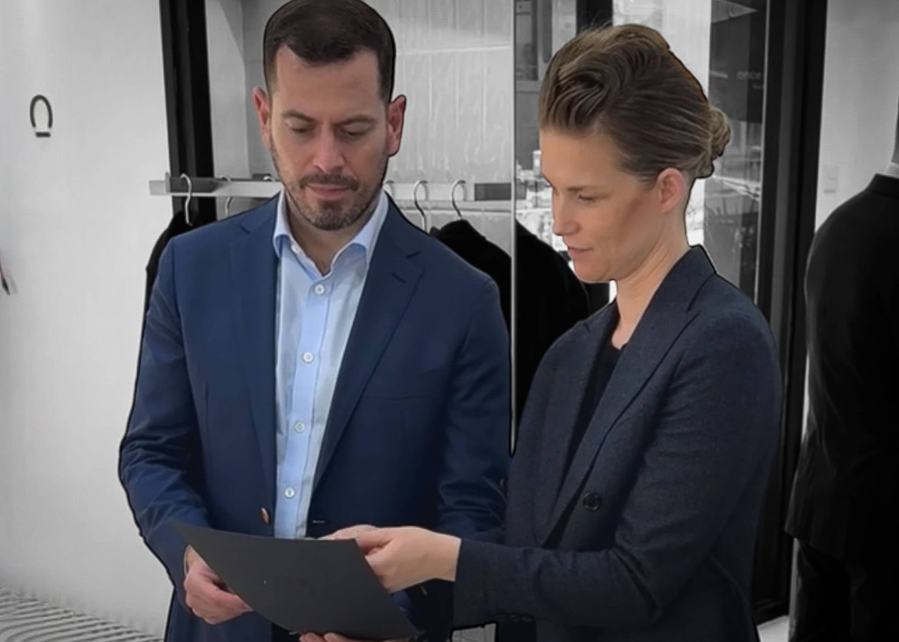 Two people in the once a day clothing store looking at suit fabrics