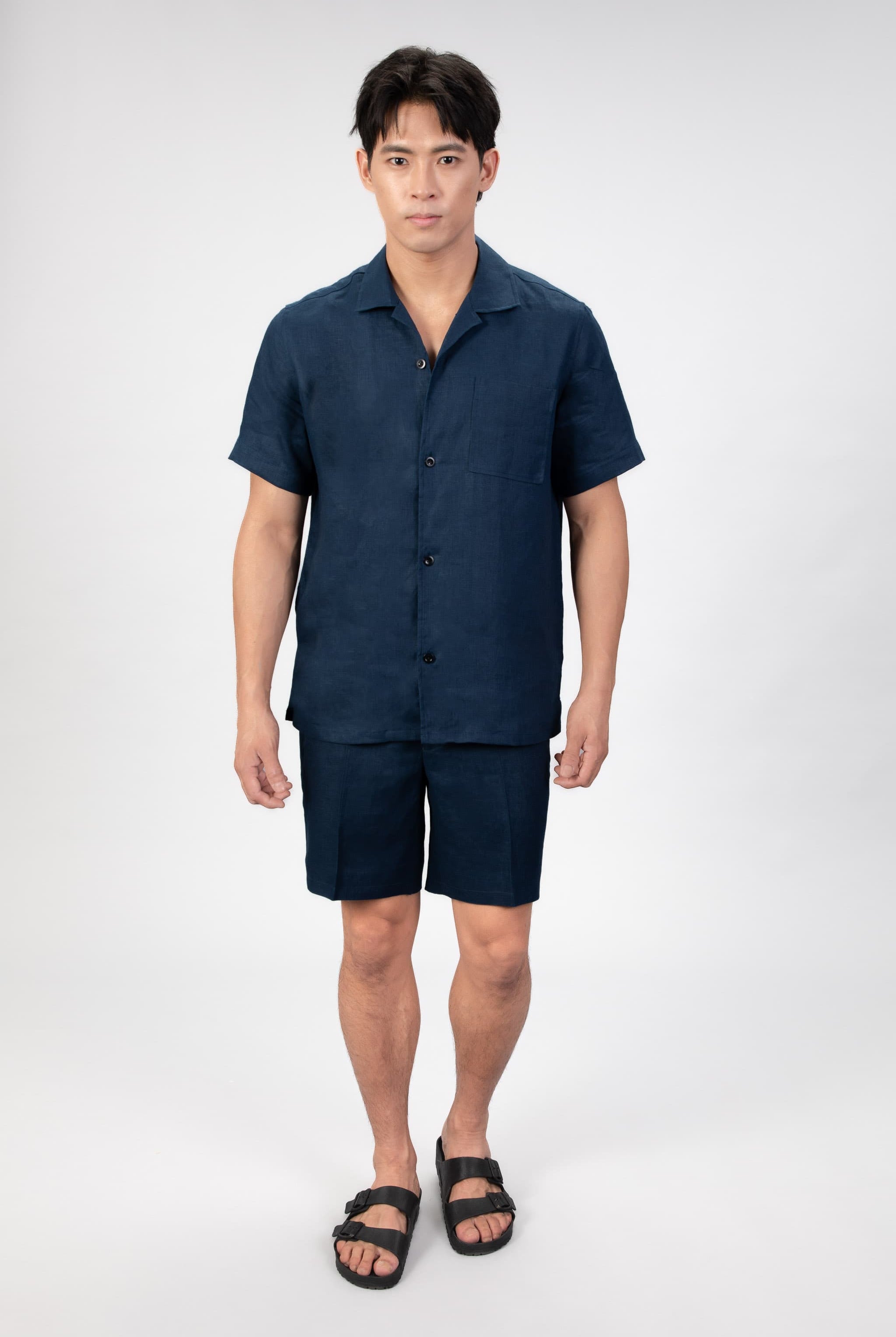 Man wearing a navy blue shirt and shorts set on a white background