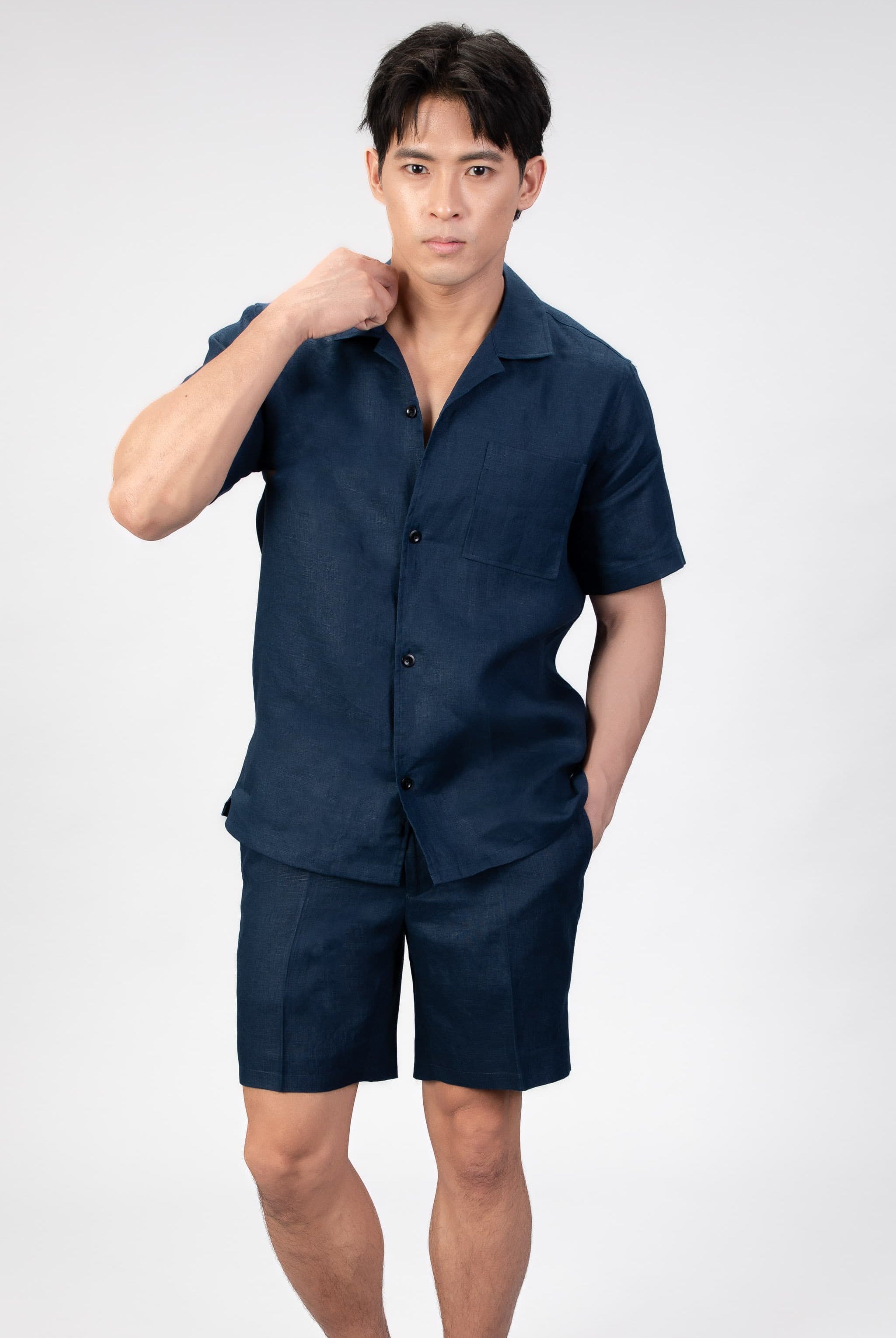 Man wearing a navy blue shirt and shorts set on a light gray background