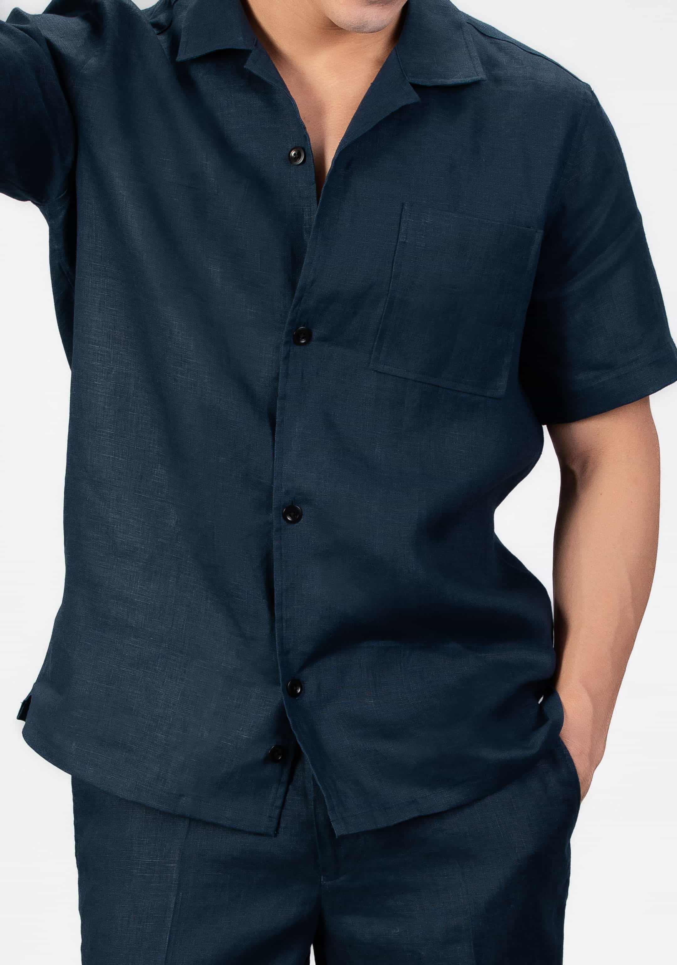 Person wearing navy blue linen set, camp collar shirt and shorts on light gray background