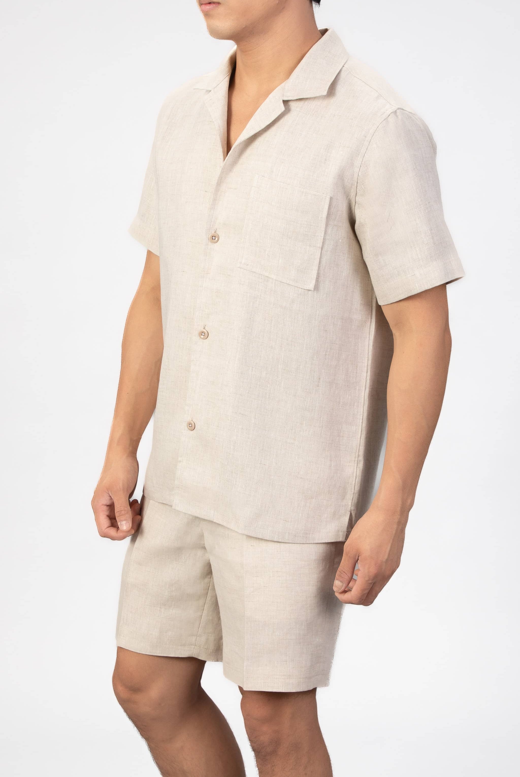 Person wearing a beige linen shirt and shorts set on a white background