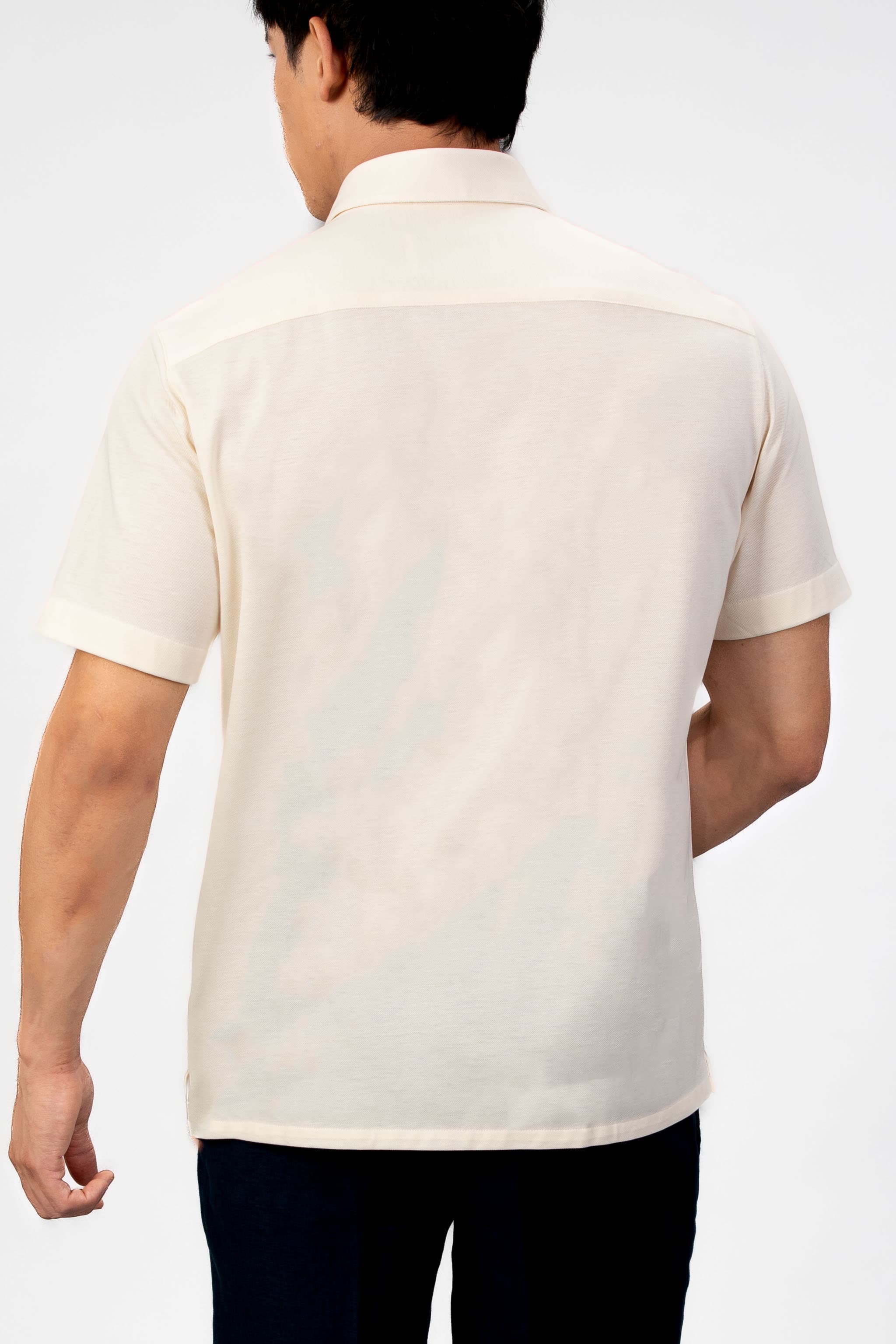 Man wearing a sand-beige piquet polo shirt sleeve shirt with linen navy shorts on a light gray background