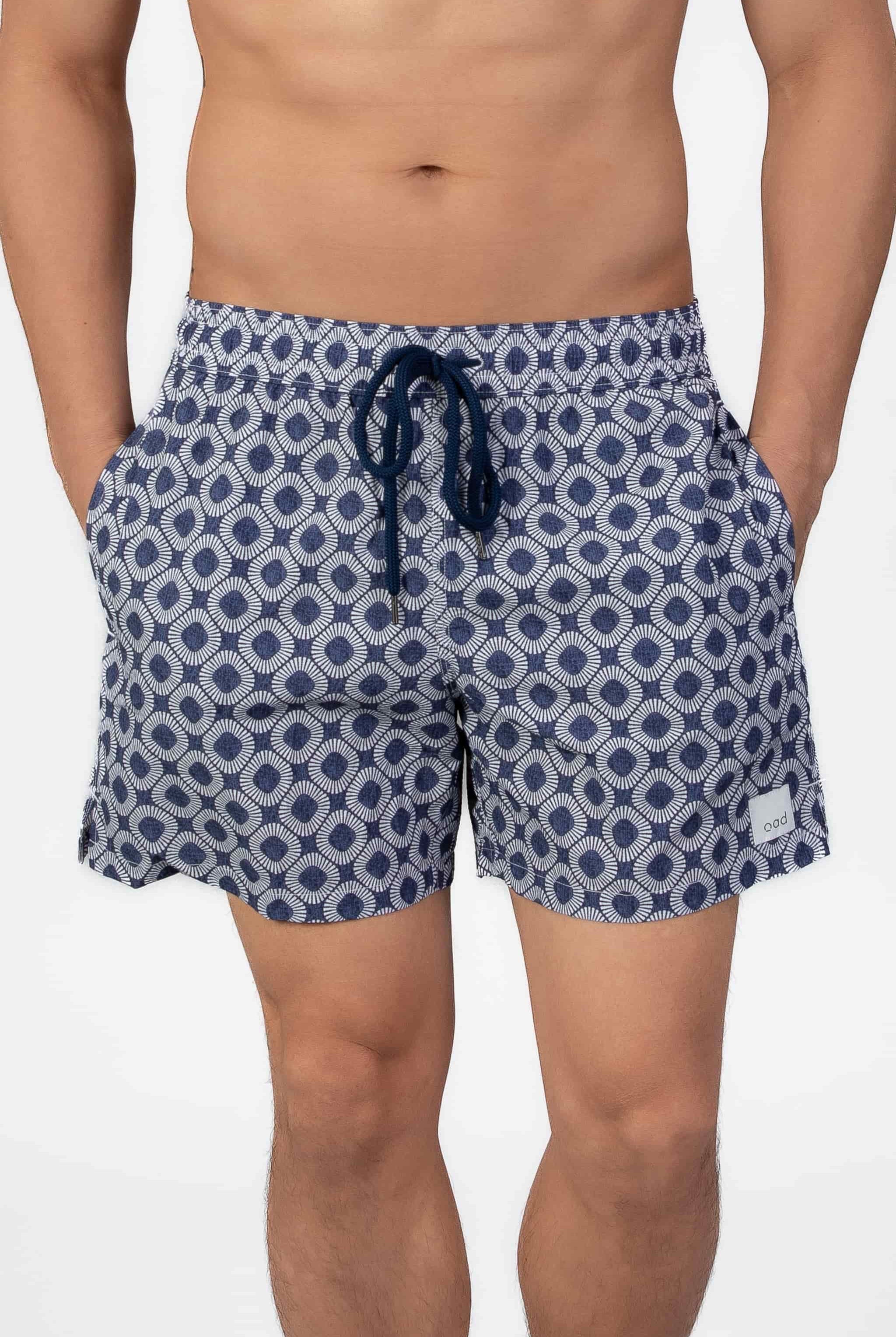 Man wearing blue patterned shorts in navy blue seersucker fabric on a plain background