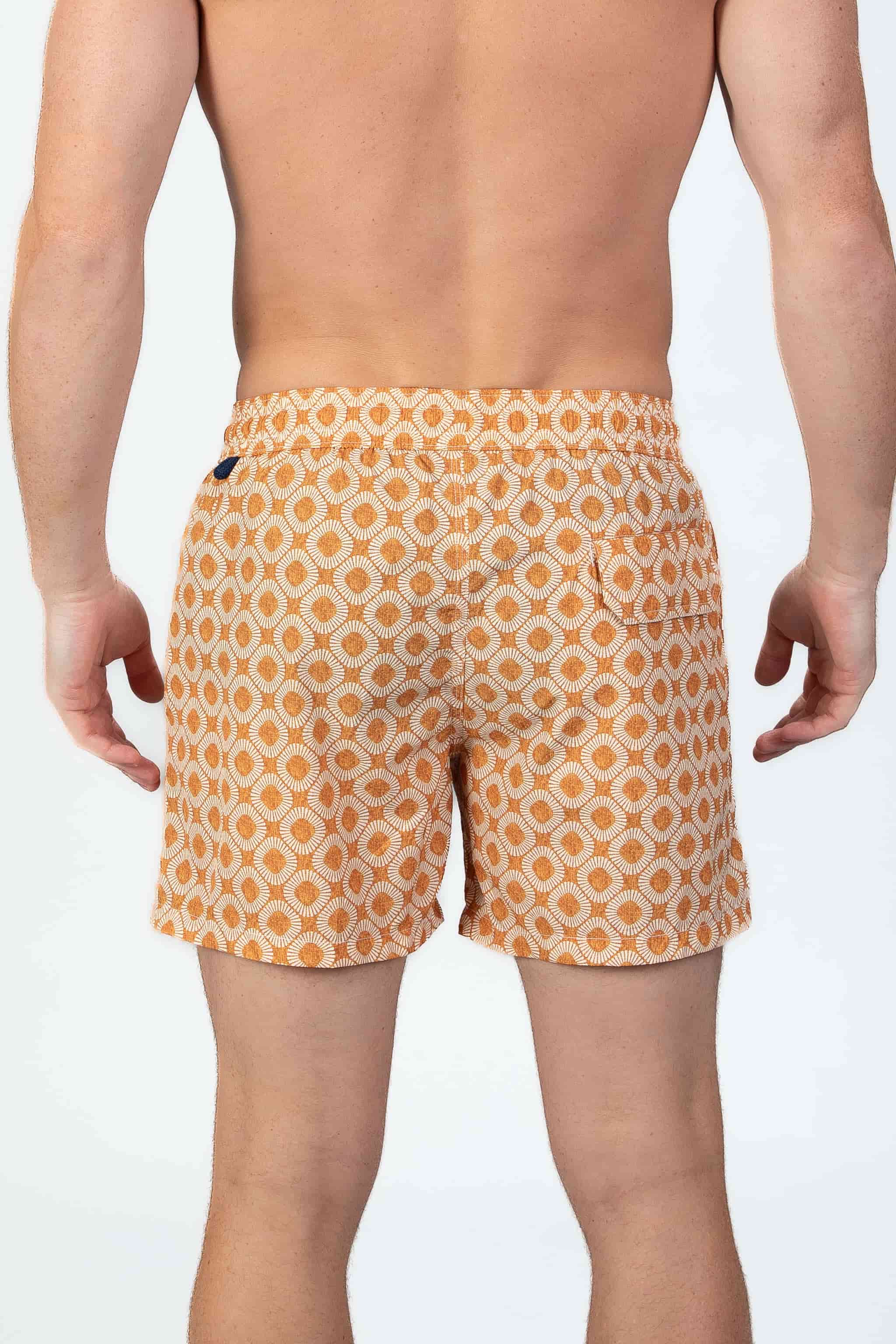 Person wearing stylish orange pattern seersucker swim shorts, back view showing the magnetic closure back pocket and textured fabric.