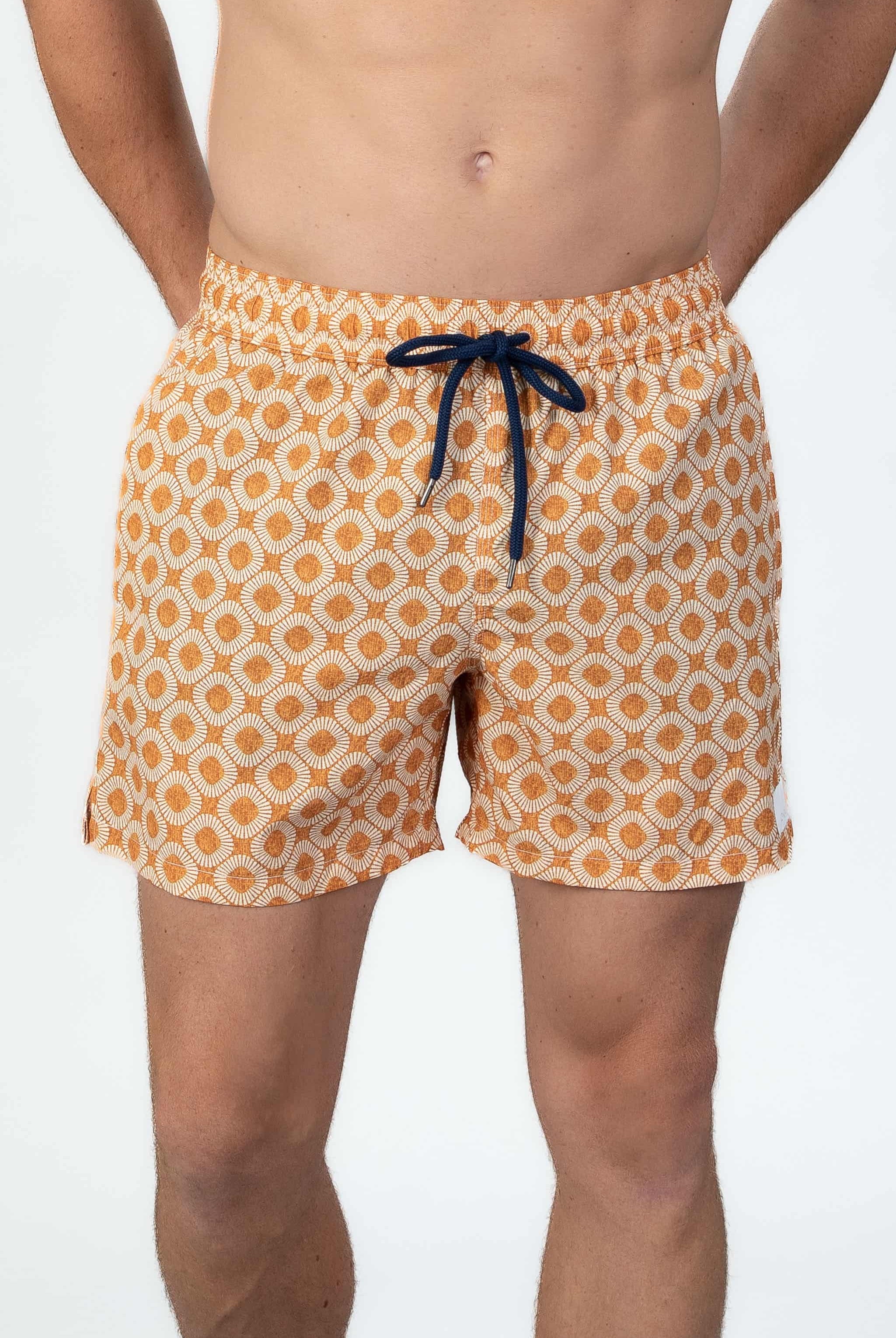 Person wearing stylish orange pattern seersucker swim shorts with string closure, front.