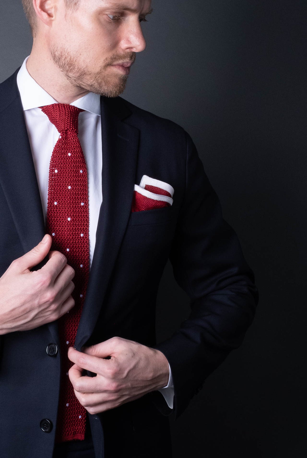 Red knitted pocket square with white frame. Made of silk in Italy paired with Matching tie.