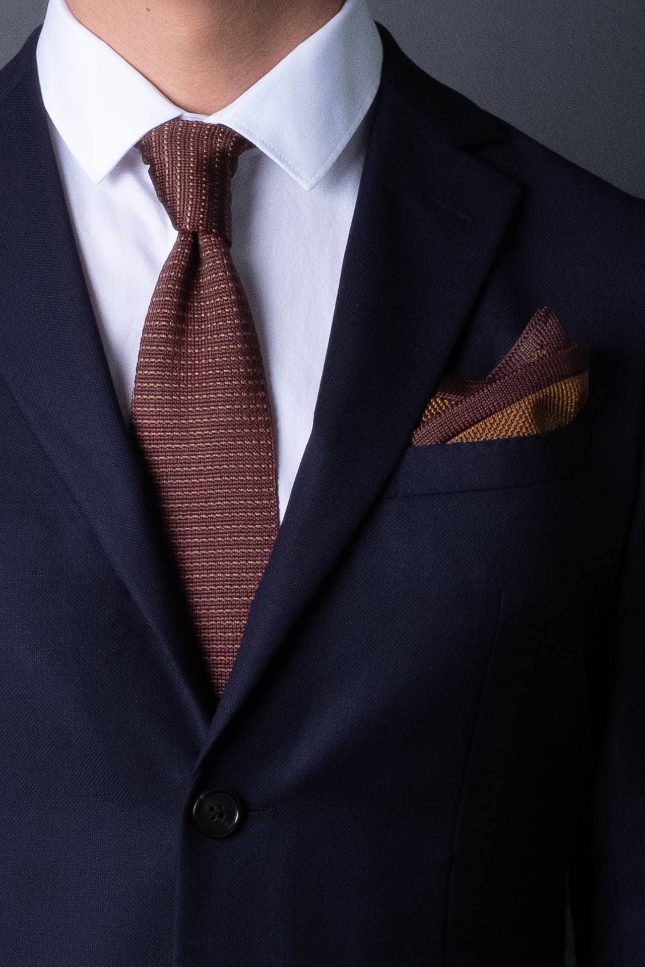 Brown knitted pocket square with dark brown boarder. Made of silk in Italy.