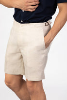 Beige sand shorts in linen worn by a person on a light gray background