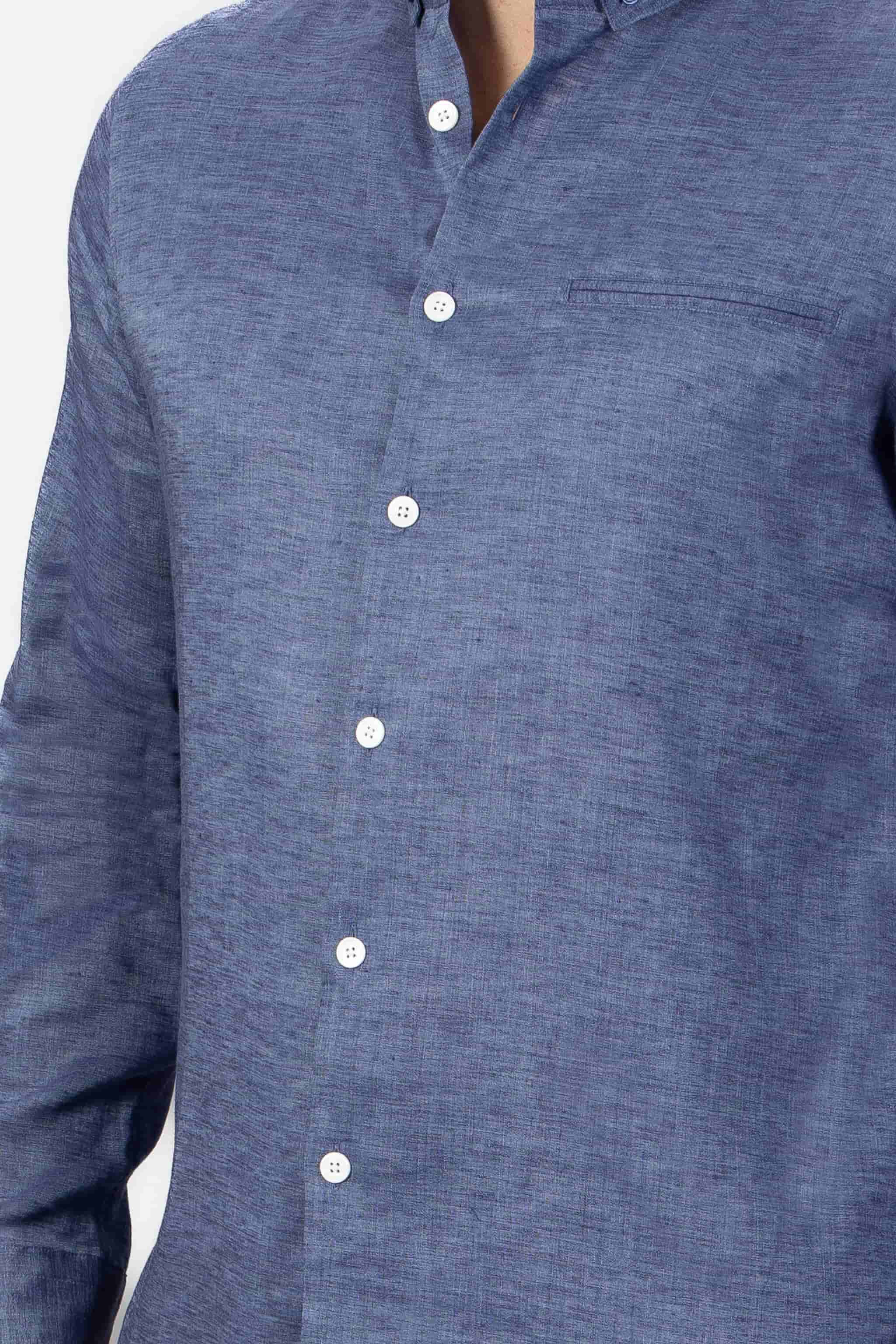 Man wearing a blue button-down shirt  in linen on a light gray background
