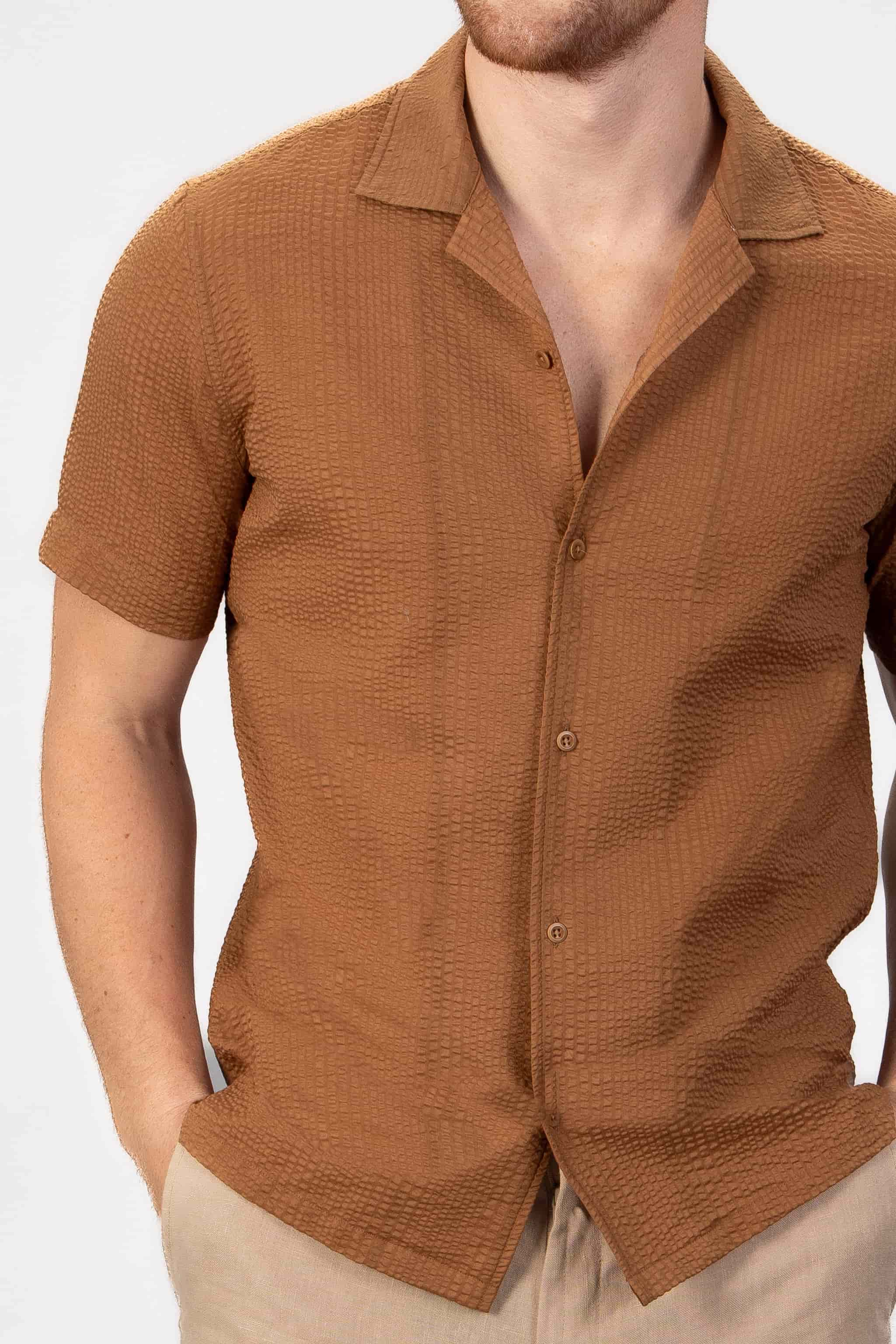 Man wearing a brown seersucker shirt on a light gray background