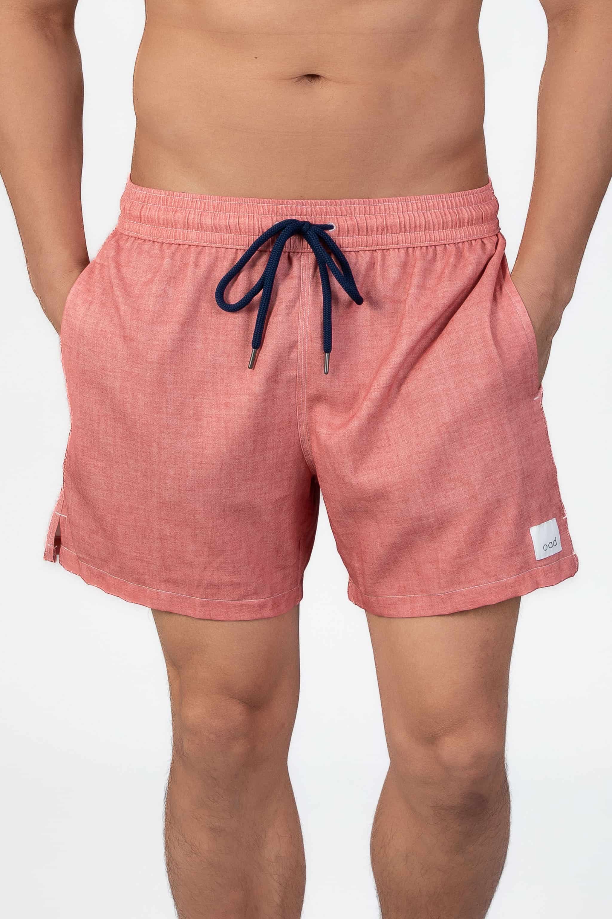 Person wearing pink-coral soft swim shorts on a light gray background
