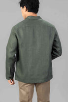 Man wearing a green linen overshirt with beige chinos on a light gray background