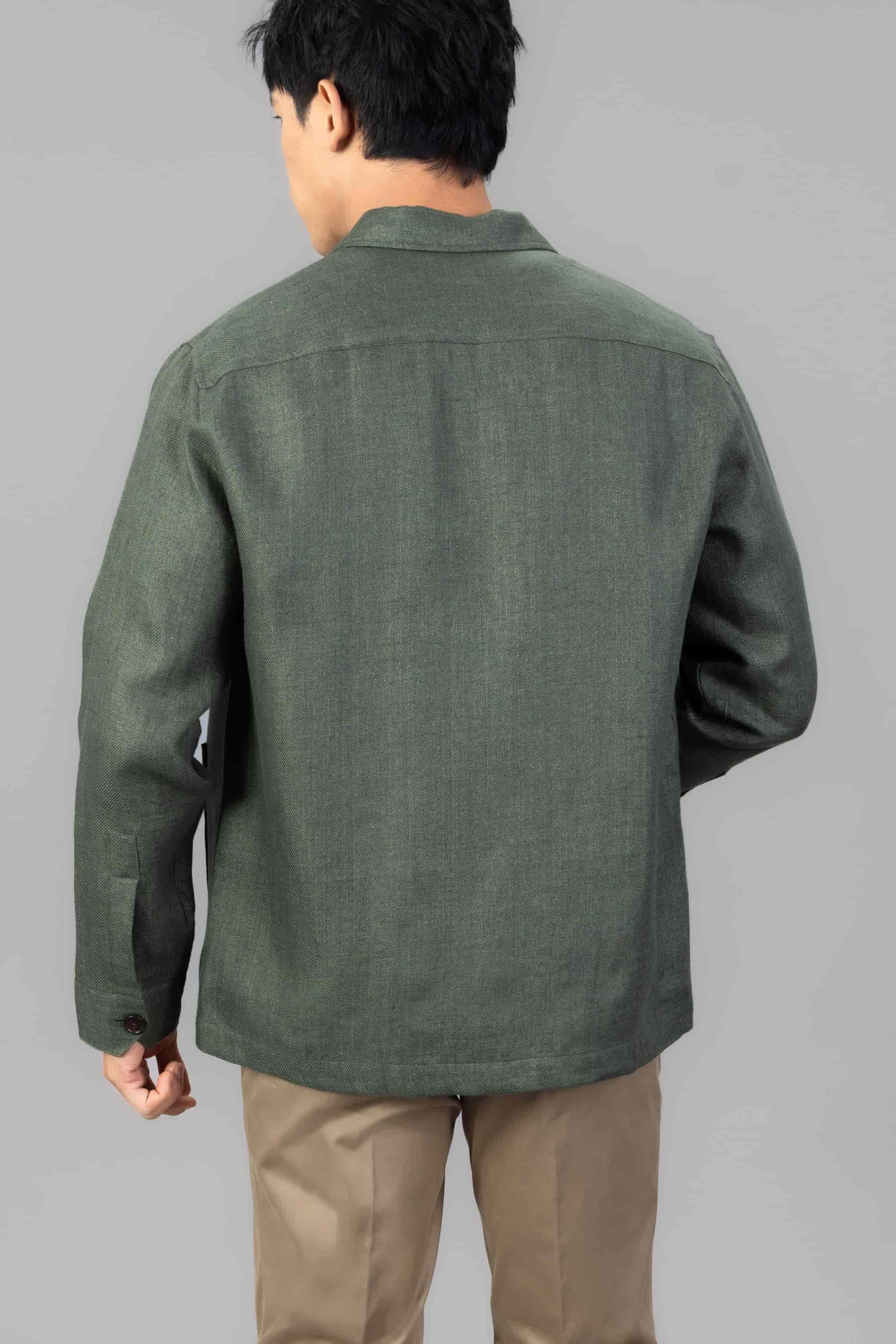 Man wearing a green linen overshirt with beige chinos on a light gray background