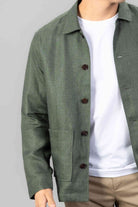 Man wearing a green linen overshirt on a white T-shirt and with beige chinos on a light gray background