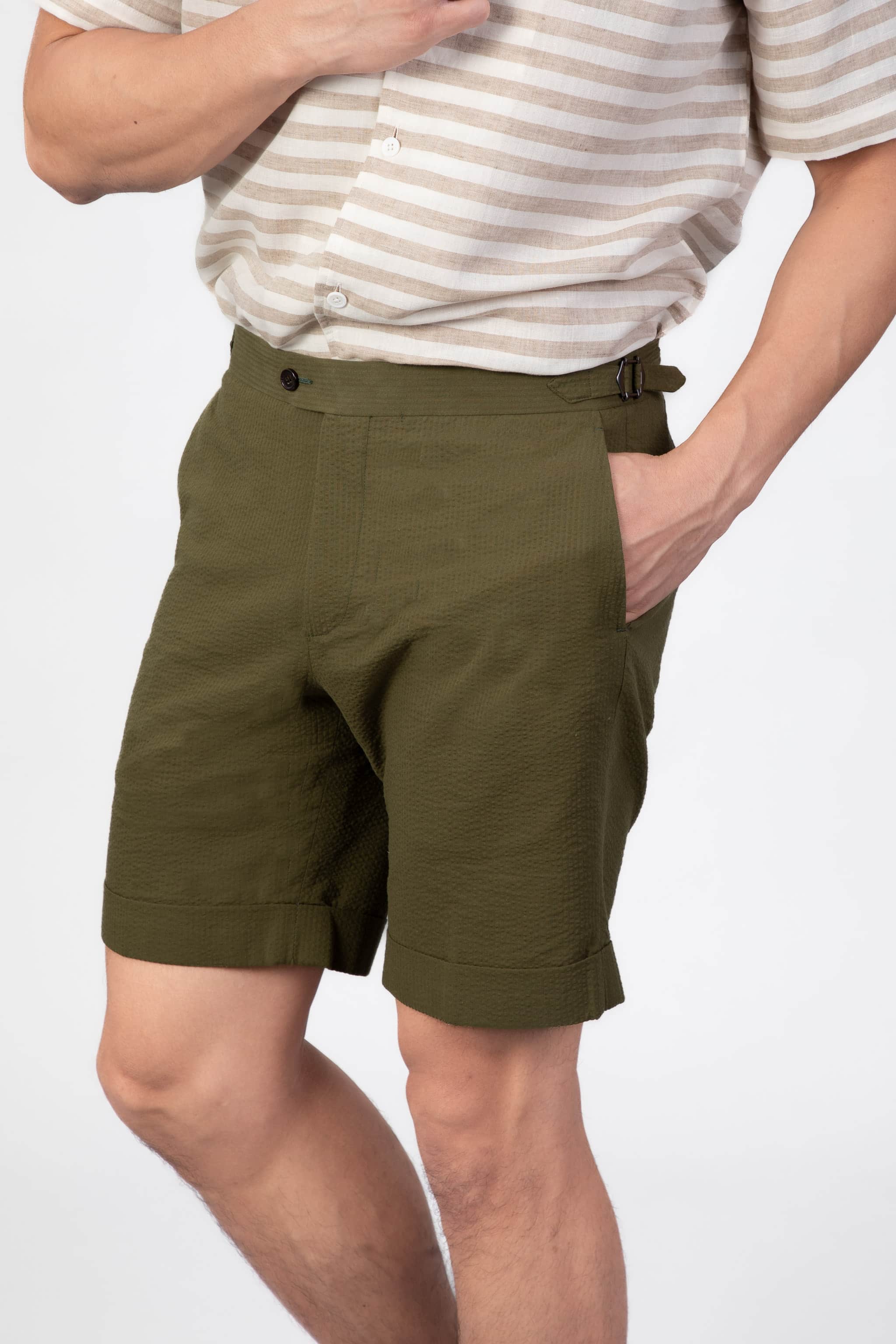 Man wearing a green seersucker shorts with side adjusters on a light gray background
