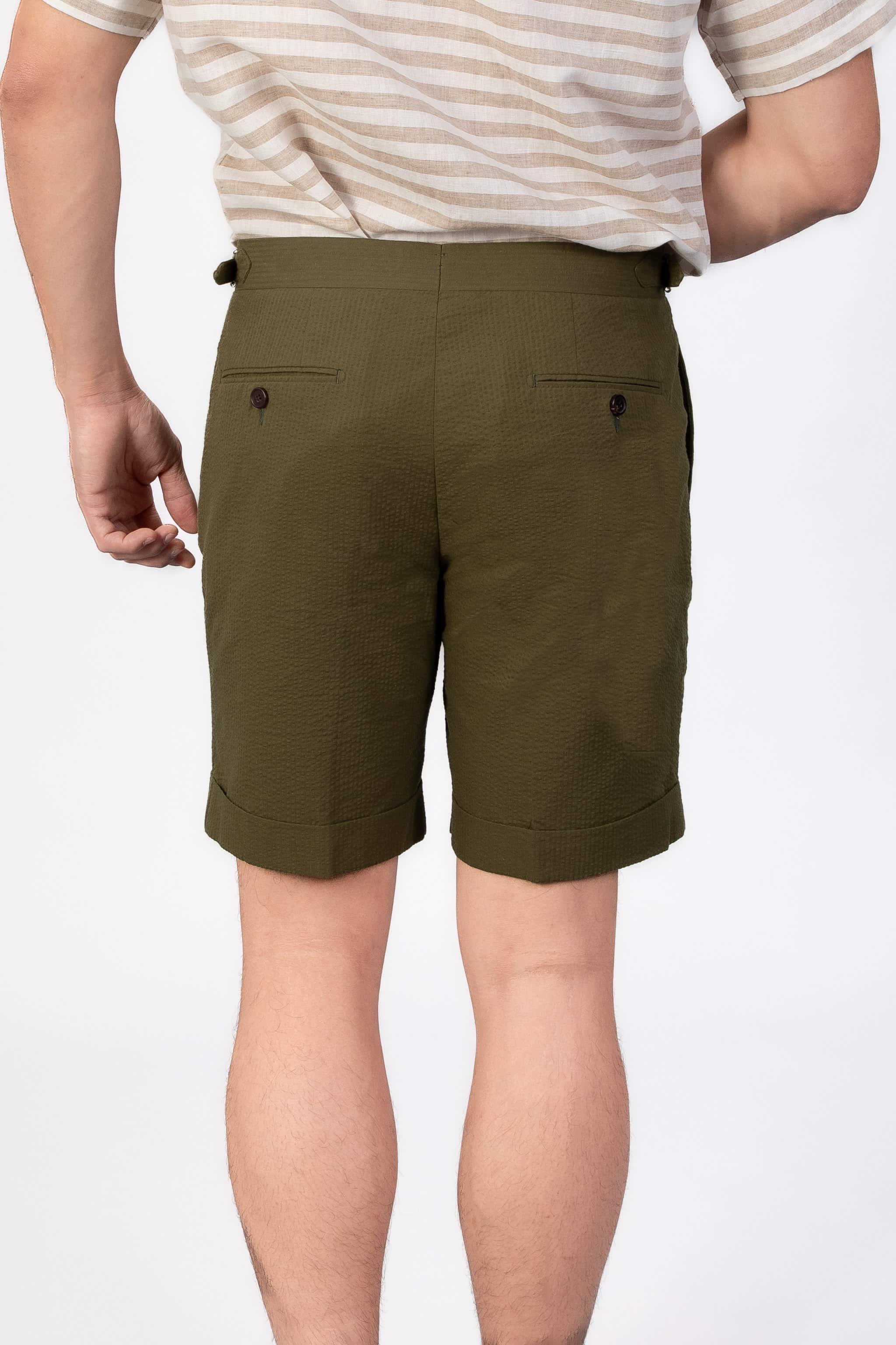 Man wearing a green seersucker shorts with two back pockets on a light gray background