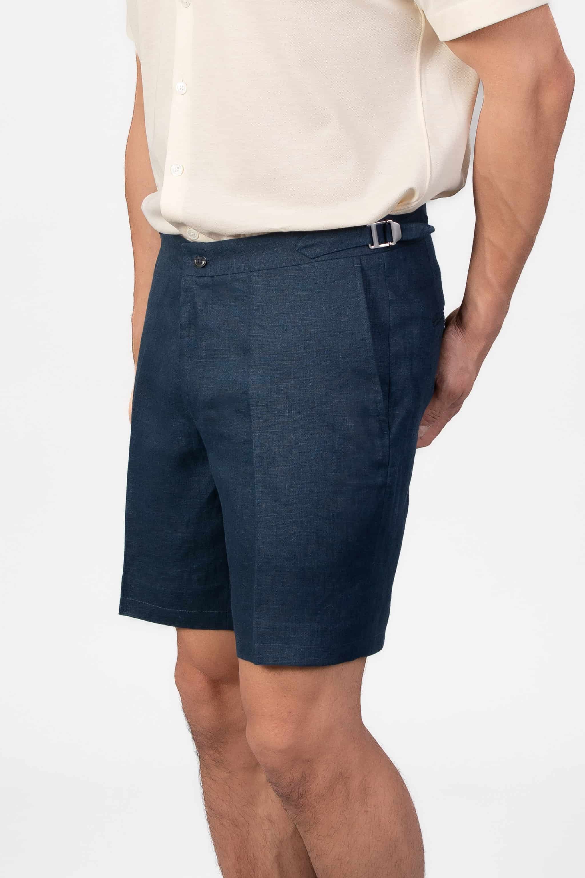 Person wearing linen navy shorts with side adjusters on a light gray background