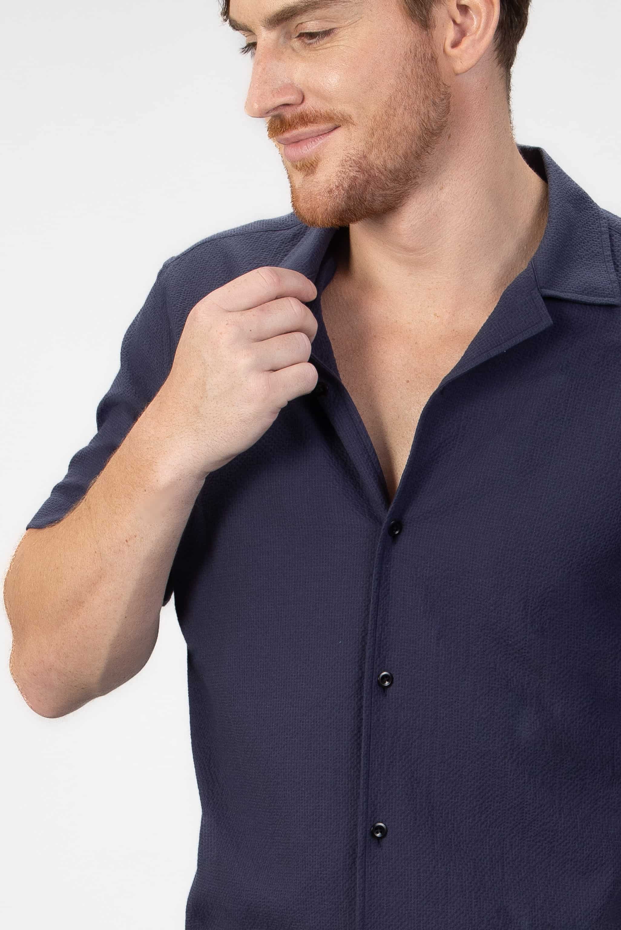 Man wearing a navy camp collar shirt on a light gray background