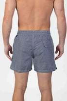 Back view of person wearing classic high end navy swim shorts with a white pattern and drawstring
