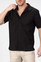 Man wearing a black short-sleeve shirt with a seersucker pattern on a white background