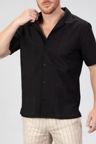 Man wearing a black short-sleeve shirt with a seersucker pattern on a white background