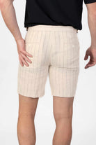 Beige pinstripe linen shorts worn by a person on a light gray background
