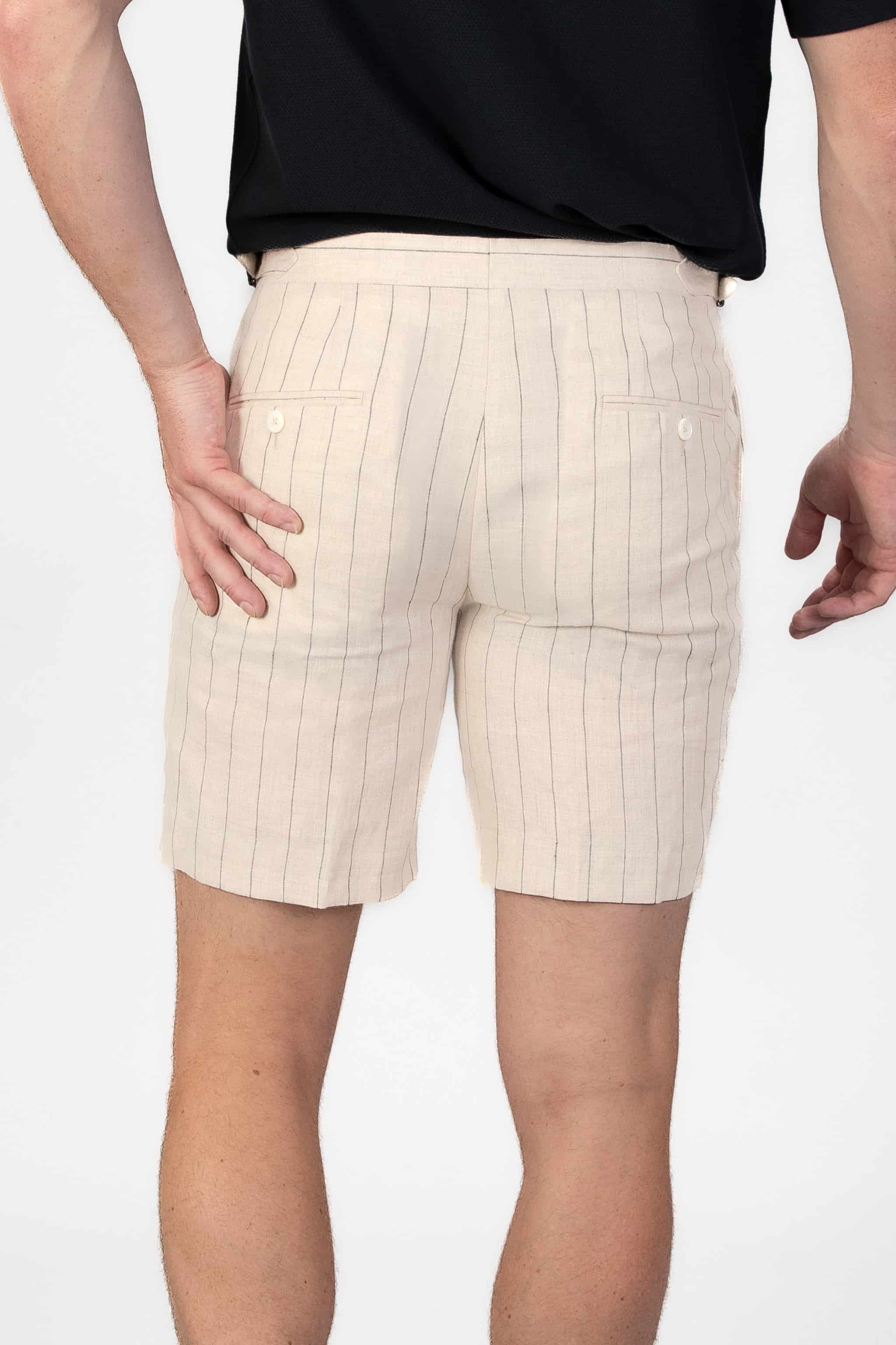 Beige pinstripe linen shorts worn by a person on a light gray background