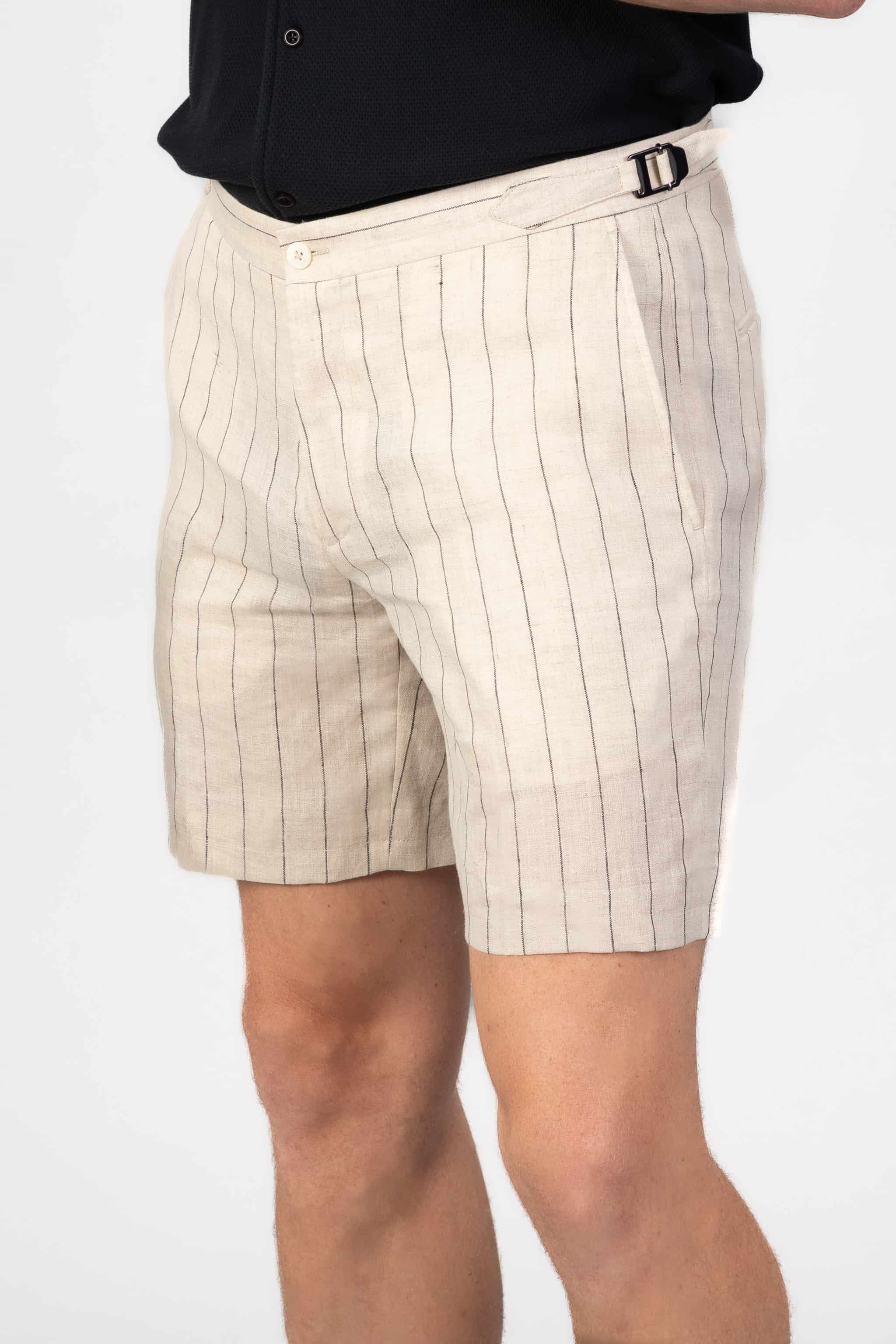 Beige pinstripe linen shorts worn by a person on a light gray background