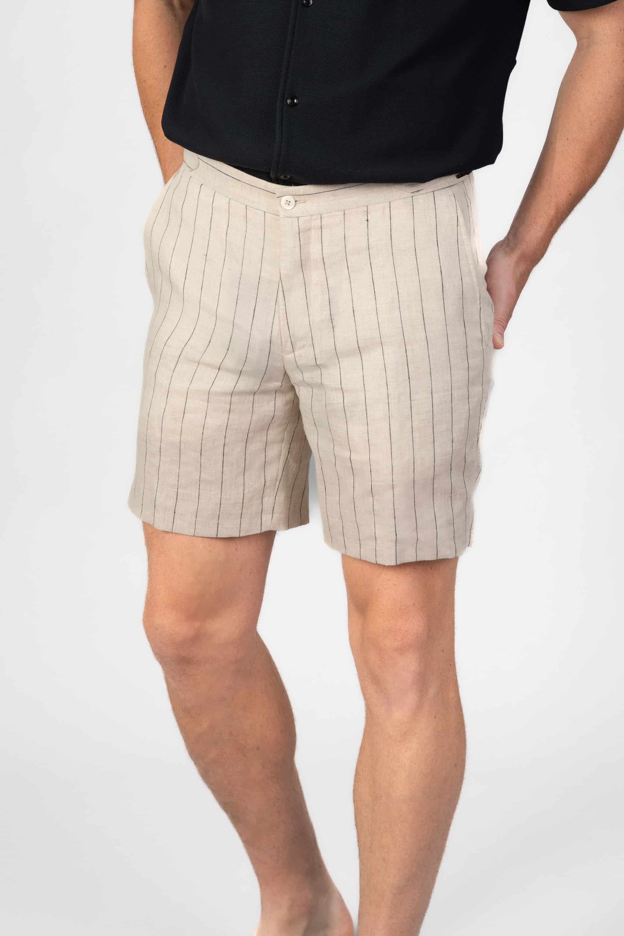 Beige pinstripe shorts worn by a person on a light gray background