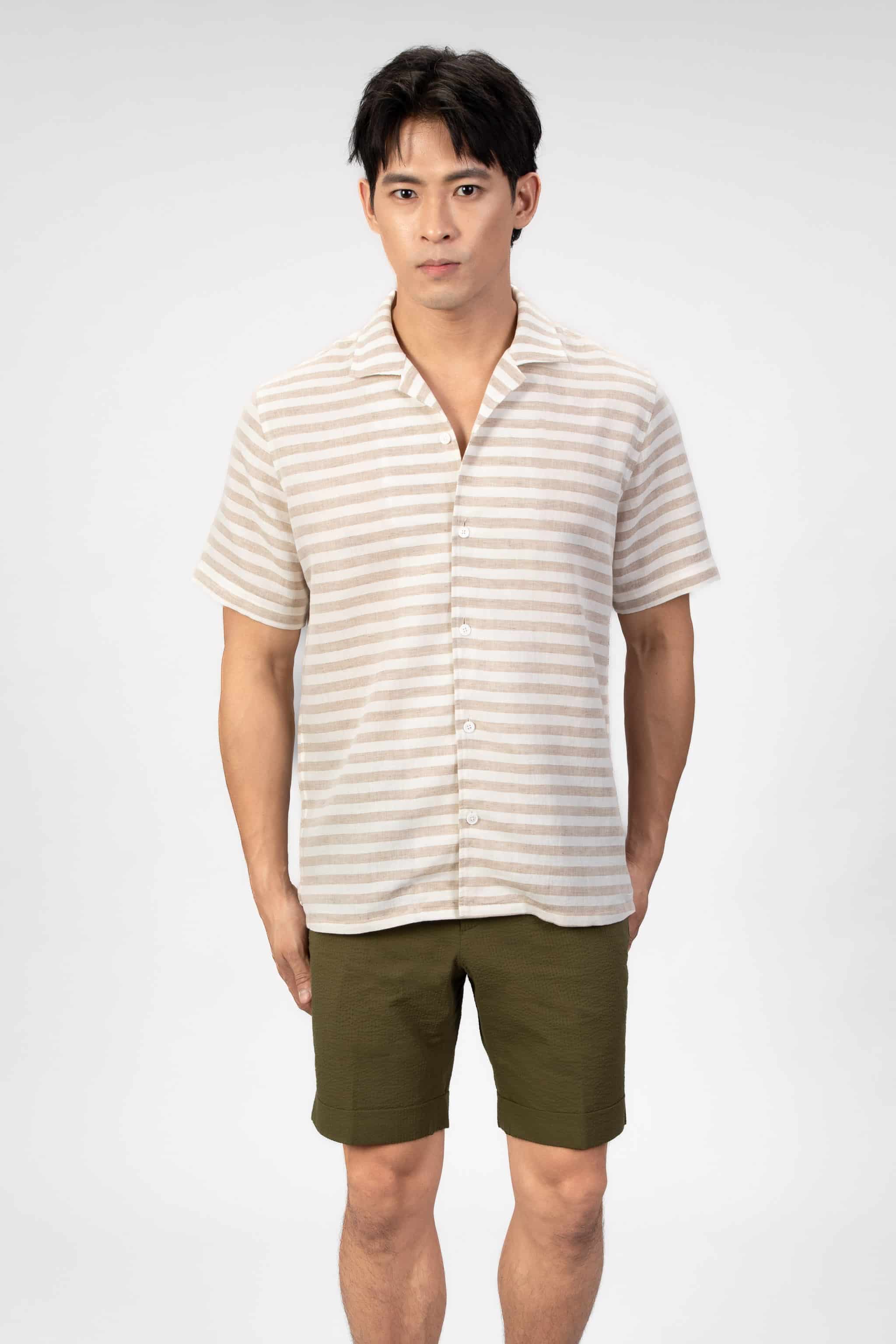 Man wearing a striped shirt and green shorts on a light gray background