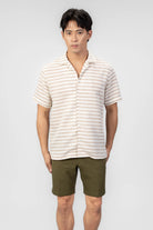 Man wearing a striped shirt and green shorts on a white background