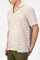 Man wearing a striped linen shirt in beige and white on a light gray background