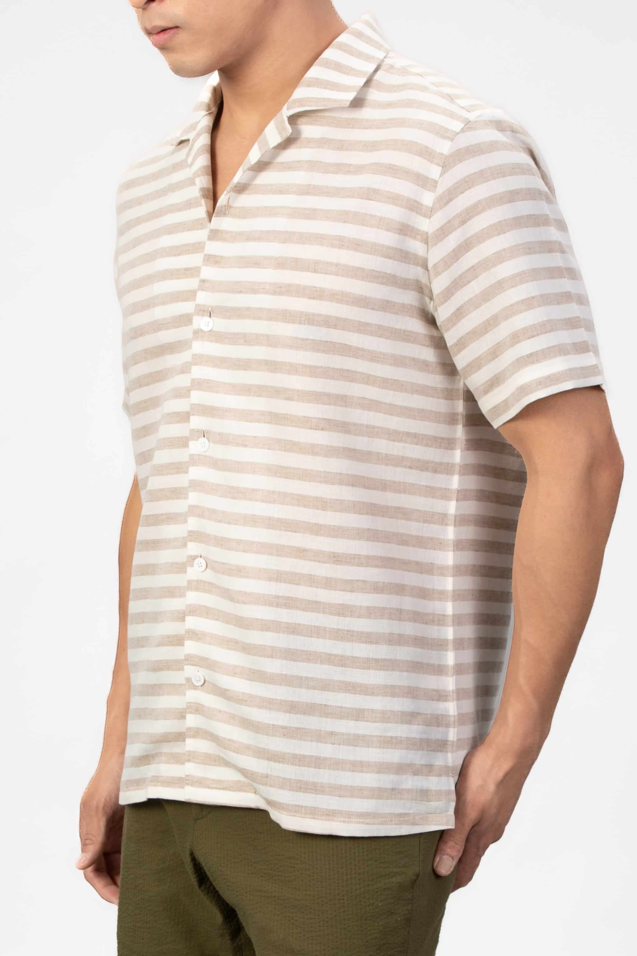 Man wearing a striped linen shirt in beige and white on a light gray background