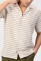 Person wearing a beige and white striped shirt against a plain background